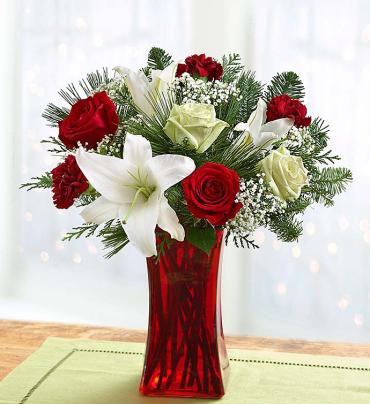 Holiday Magic -  Our enchanting bouquet of red roses, white lilies, alstroemeria and evergreens brings holiday magic to the door. Hand-designed by our expert florists in a red gathering vase accented with a festive Santa belt, it's a spellbinding surprise for that special someone.   Item # 99104 