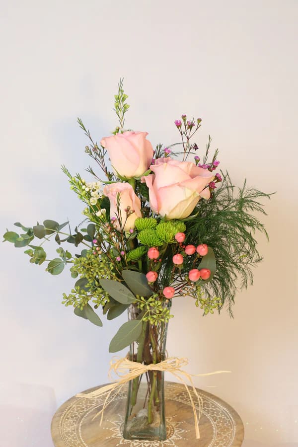 Mini Angel - This sweet arrangement comes with three roses and seasonal greenery with other adornments such as hypericum berries or smaller, filler flowers.