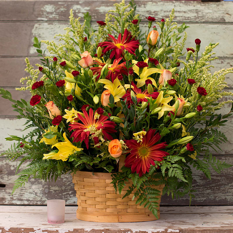 Grace Grace - When you want to express your warmest condolences, this remembrance basket will show just how much you care. This arrangement is perfect for a funeral service or even delivered to the home to cheer the recipient and make a lasting impression. Lilies, Red Mums, Roses, and Mini Carnations in warm colors will make this basket stand out from the crowd.