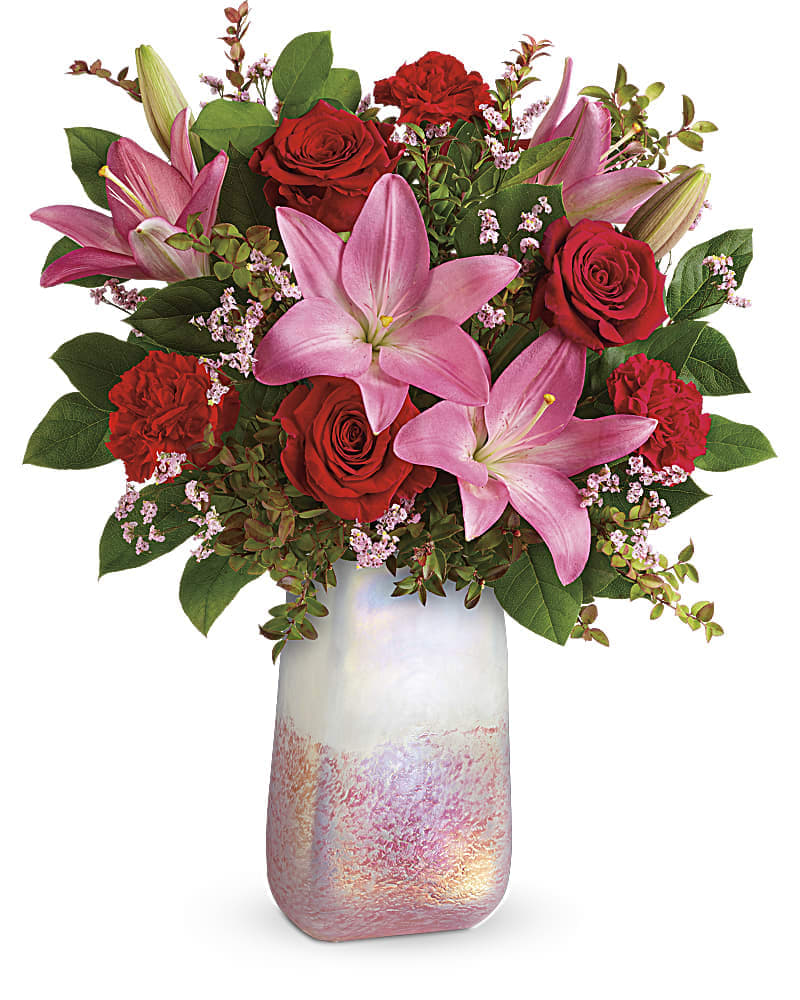Teleflora's Pretty In Quartz Bouquet - Inspired by the rose quartz gemstone that symbolizes love, this shimmering, hand-blown art glass vase is the perfect backdrop for this romantic pink and red bouquet. This bouquet features red roses, pink asiatic lilies, red carnations, pink limonium, red huckleberry, and lemon leaf.
