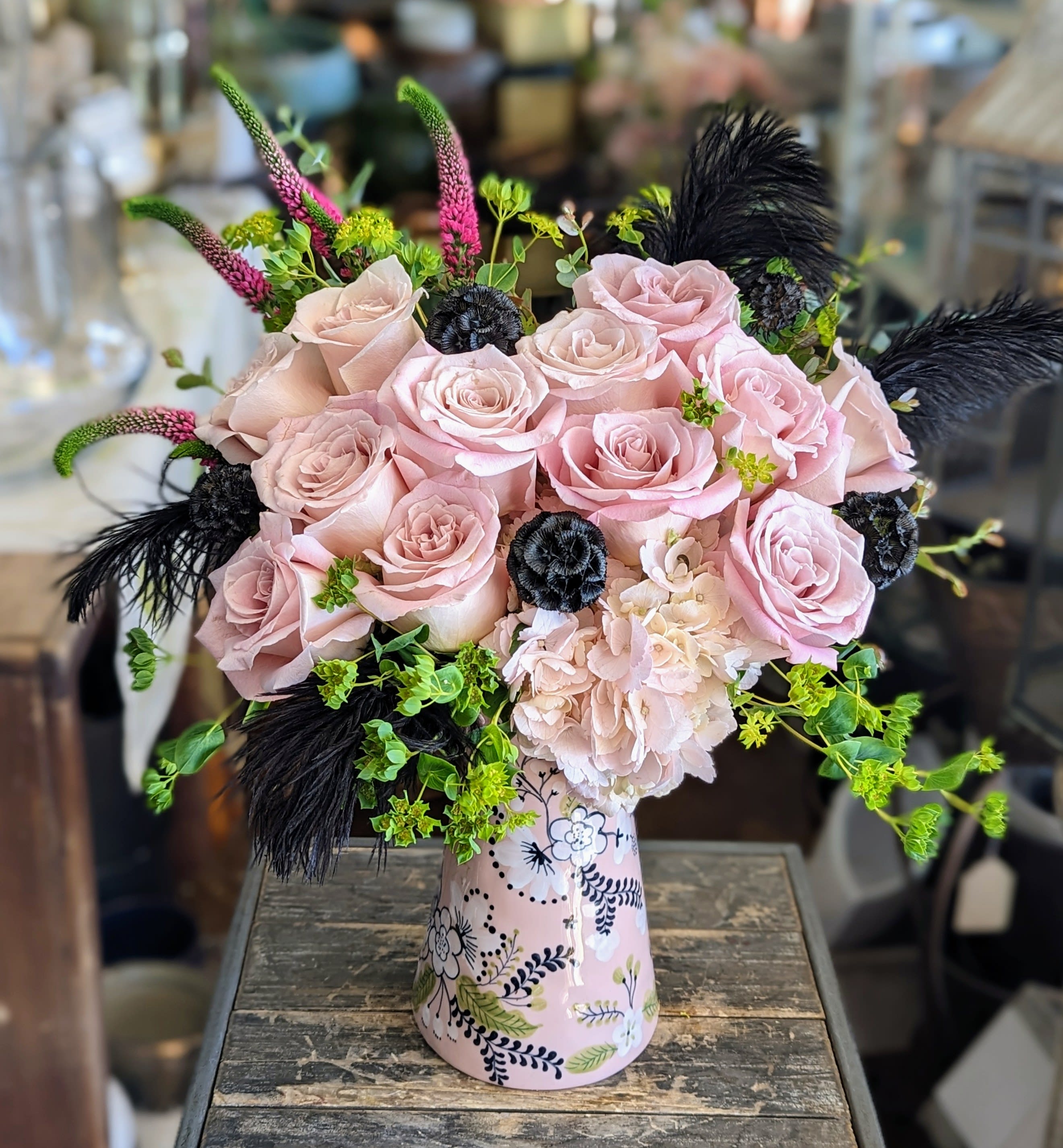Bloomsbury - Pale pink roses, veronica, and blush hydrangea, accented with black feathers and black scabiosa pods arranged in a elegant keepsake vase.