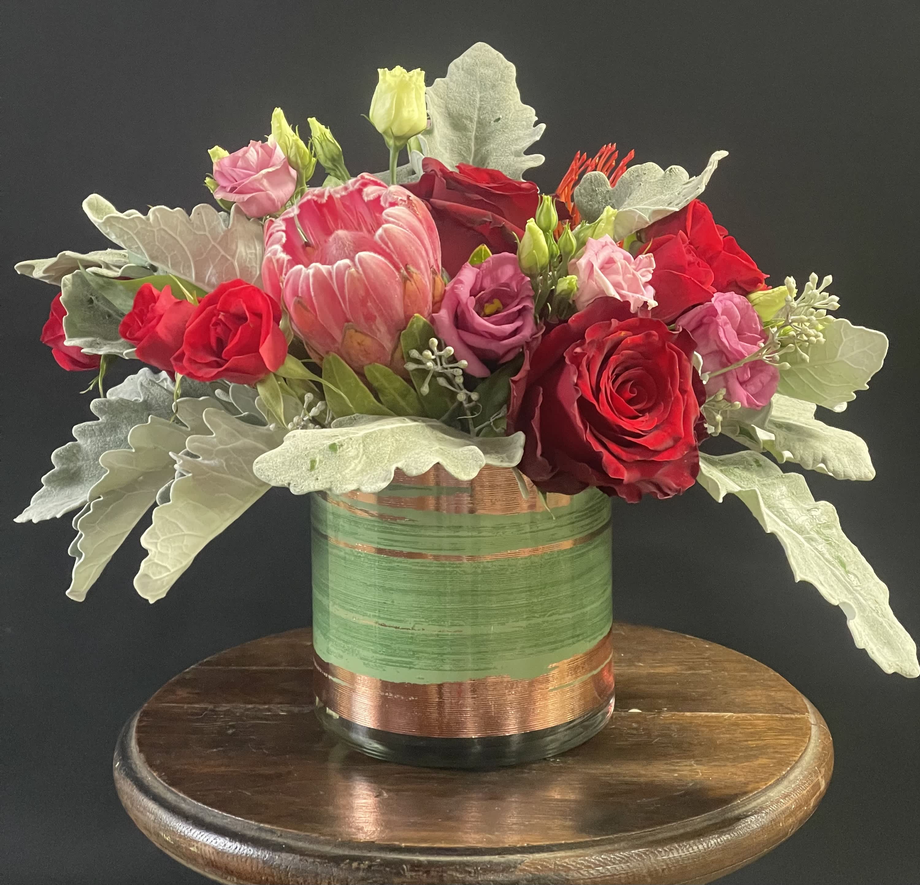 Tropical Expression Bouquet  - A compact design with tropical blooms like protea, pin cushion, or ginger.  Nestled among them are other blooms like roses, spray roses, and lisianthus.  Tropical flowers may vary depending on availability.