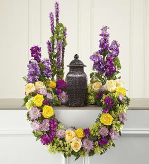 Garden of Grace - This masterpiece of floral sympathy creates a beautiful and reverential tabletop setting for an urn holding the cremated remains of your loved one. Handcrafted by Andes Florist, this stunning and original creation is perfect for formal visitation or memorial services. Constructed on a modified wreath frame, it combines cream and yellow roses, fuchsia Dianthus, purple Liatris and stock, lavender cushion pompons, green trachelium and hydrangea all accented with lush greenery including ivy vines.