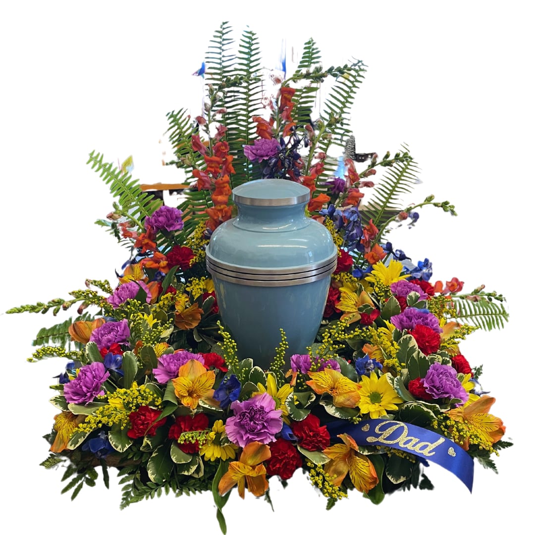 Eternal Tribute Urn Halo Eternal Tribute Urn Halo - The Eternal Tribute Urn Halo is a splendid and colorful expression of love and remembrance. This arrangement encircles the space where a cremation urn would be placed, with a vibrant bounty of flowers. Vivid blues, purples, reds, and yellows come together in a lush display of snapdragons, carnations, and alstroemeria, symbolizing the richness and variety of a life fully lived. Solidago and ferns add texture and depth, creating a natural backdrop for the bright blossoms. A customizable sash adds a personal touch, making it a heartfelt centerpiece for a memorial service to celebrate and honor a beloved father's memory. *Note* - Cremation urn in picture is not included. Flower arrangement only. - Customizable sash preference needs to be included in the special instructions during checkout. If we do not receive any special instructions we will not include a sash.