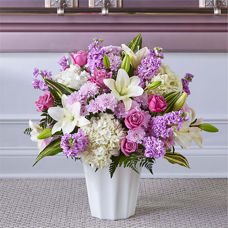 Heaven Sent Floor Basket - HEAVEN SENT FLOOR BASKET Blessings and prayers sent from above are captured in this stunning lavender and white arrangement. Each gorgeous bloom in our Heaven Sent Floor Basket is designed to bring solace during difficult times. While the lilies may initially arrive in bud form, they beautifully transform as they open.