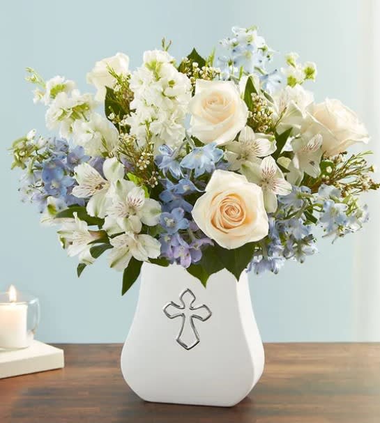 Sacred Blessings Blue and White - One thoughtful gesture can bring peace and comfort when it’s needed most. Our elegant arrangement of soft blues and whites is hand-arranged in our white, ceramic Sacred Blessings Vase, featuring a silver embossed cross. It’s a beautiful reminder that hope and love live on in our memories.  All-around arrangement with light blue delphinium, white roses, Peruvian lilies (alstroemeria), stock and waxflower; accented with assorted greenery. Artistically designed in our Sacred Blessings Vase, an enduring symbol of hope and eternal love, an elegant contemporary ceramic design with traditional regal styling and a silver embossed cross; measures 6.5&quot;H x 6&quot;L x 2.5&quot;W Arrangement measures approximately 18&quot;H Appropriate for sending to the service and to the homes of family or friends. To ensure lasting beauty, lilies may arrive in bud form and will fully bloom over the next few days.