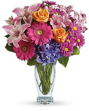 Wondrous Wishes by Teleflora - Awe and wonder. That's what's included in this magical bouquet. It's a beautiful mix of radiant blossoms in a stunning glass vase. Brilliant blue hydrangea, orange roses, light pink asiatic lilies, hot pink gerberas, pink alstroemeria, purple chrysanthemums and more fill a fabulously feminine vase. Send wonder with your lovely wishes!
