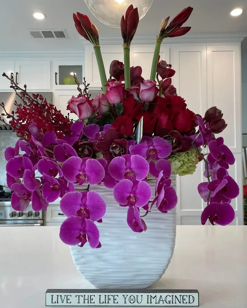 Hummingbird Lane in Purples and Red roses - Make the moment unforgettable with Dave's Flowers, your trusted local florist in Los Angeles, presenting an elegant blend of Amaryllis, Hydrangeas, Roses, and cascading Orchids arranged in a tall, striking ceramic vase. Watch as the eyes of your loved one light up at the first glance of this sophisticated floral masterpiece.  Offering Same-Day Flower Delivery in Los Angeles, we specialize in transforming emotions into exquisite arrangements. Our carefully curated selection of Amaryllis, Hydrangeas, Roses, and Orchids is designed to captivate and enchant, ensuring that your special moments are adorned with timeless beauty.  Elevate your gifting experience with the stunning contrast of colors and textures in our tall ceramic vase. Dave's Flowers understands the importance of creating lasting memories, and our floral arrangements are crafted with precision and passion.  Surprise your loved one with the elegance of Amaryllis, the lushness of Hydrangeas, the timeless beauty of Roses, and the graceful allure of cascading Orchids. Explore Dave's Flowers today for a diverse selection of floral expressions that leave a lasting impression. Trust us to make your moments extraordinary.