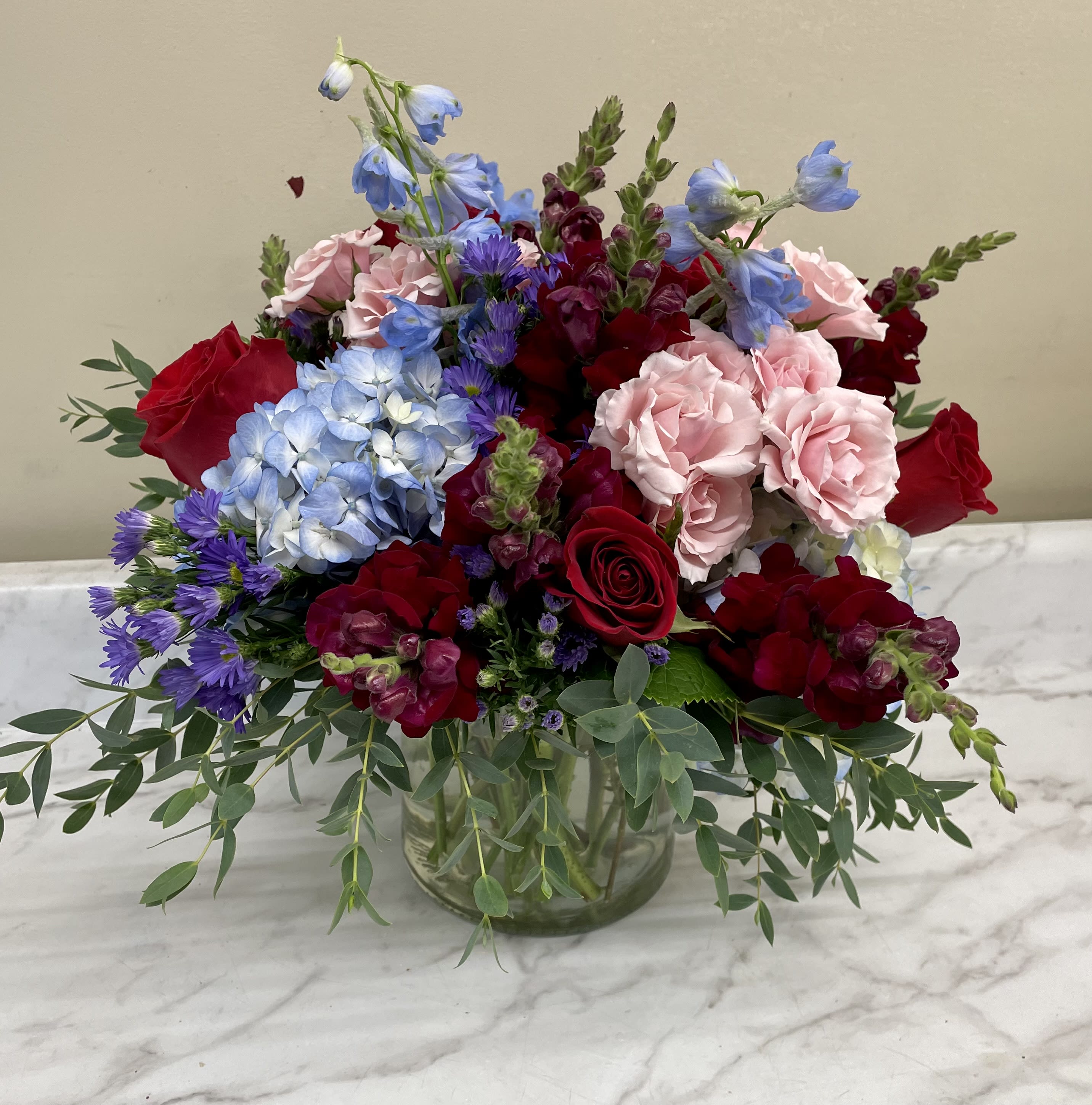 Mixed burgundy, reds, blues, and deep purple flowers in vase - A mixture of flowers of burgundy, reds and blues 