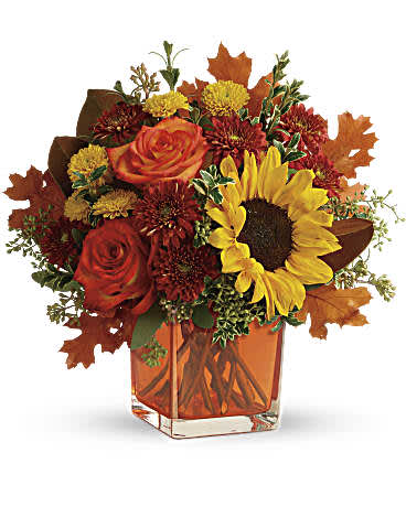Teleflora's Hello Autumn Bouquet - Sunny sunflowers and radiant roses in a happy orange cube vase bring joy to any fall dÃ©cor! This bright bouquet includes orange roses, yellow sunflowers, gold cushion spray chrysanthemums, rust cushion spray chrysanthemums, seeded eucalyptus, oregonia, and magnolia leaves. Deliverd in an orange cube.