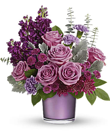 Always Amethyst Bouquet - Shimmering with the beauty of a faceted amethyst, this luxurious rose bouquet is presented in a lustrous purple vase, the perfect way to spoil your special someone! This pretty bouquet includes lavender roses, lavender carnations, lavender stock, purple cushion spray chrysanthemums, purple button spray chrysanthemums, dusty miller, seeded eucalyptus, and lemon leaf. Delivered in Teleflora's Purple Amethyst Polished Gem Cylinder. Orientation: All-Around