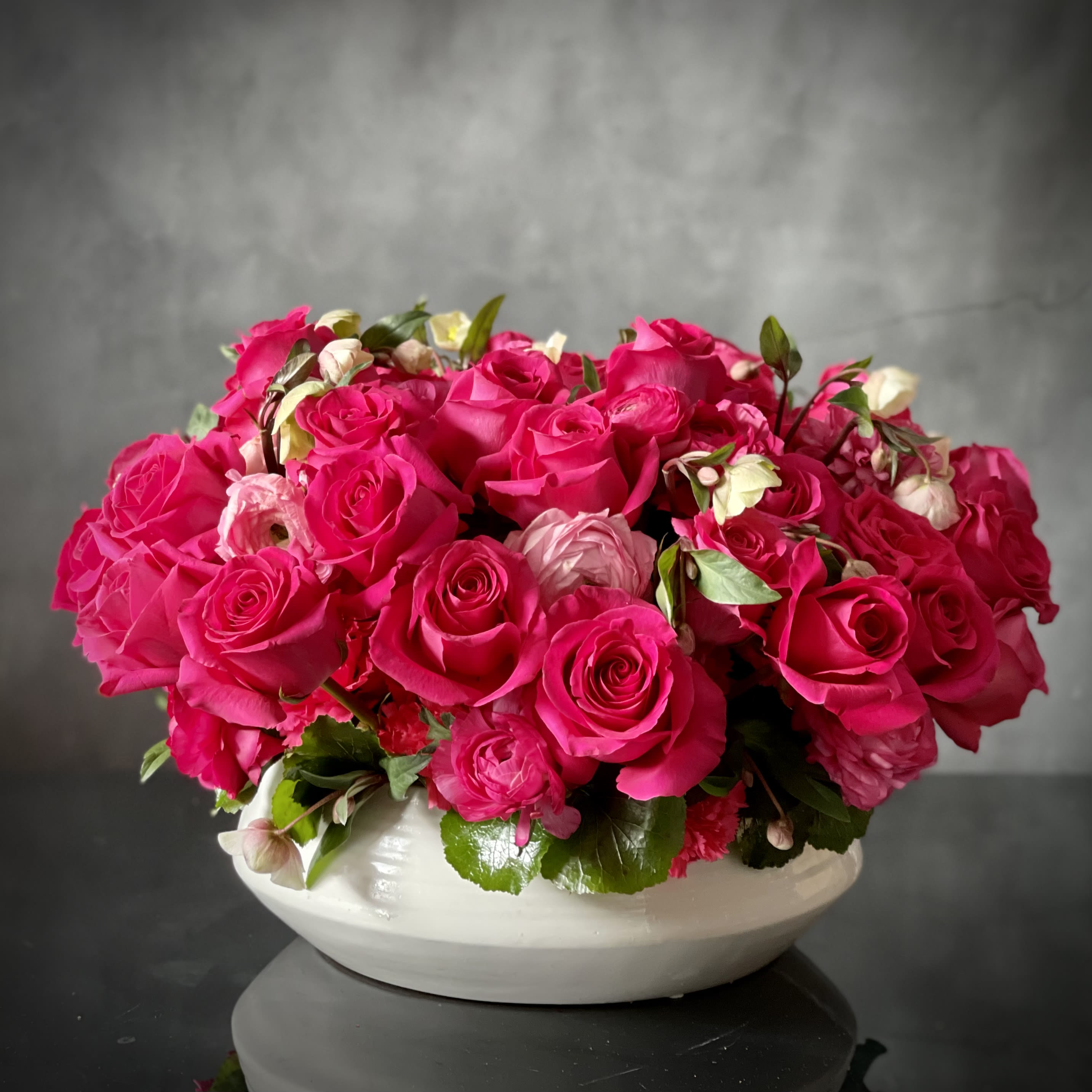 Hot hot hot  - A variety of Roses and Ranunculus in deep blushing hues clustered in a low modern vase