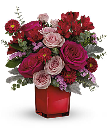 Teleflora's Loving Bunch Bouquet - A loving bunch, indeed! Show them you care with high-fashion hot pink roses in a bold crimson glass cube that's also a cool candleholder! This bold bouquet features hot pink roses, pink spray roses, red alstroemeria, red matsumoto asters, pink sinuata statice, dusty miller and spiral eucalyptus. Delivered in Teleflora's Color Splash Cube