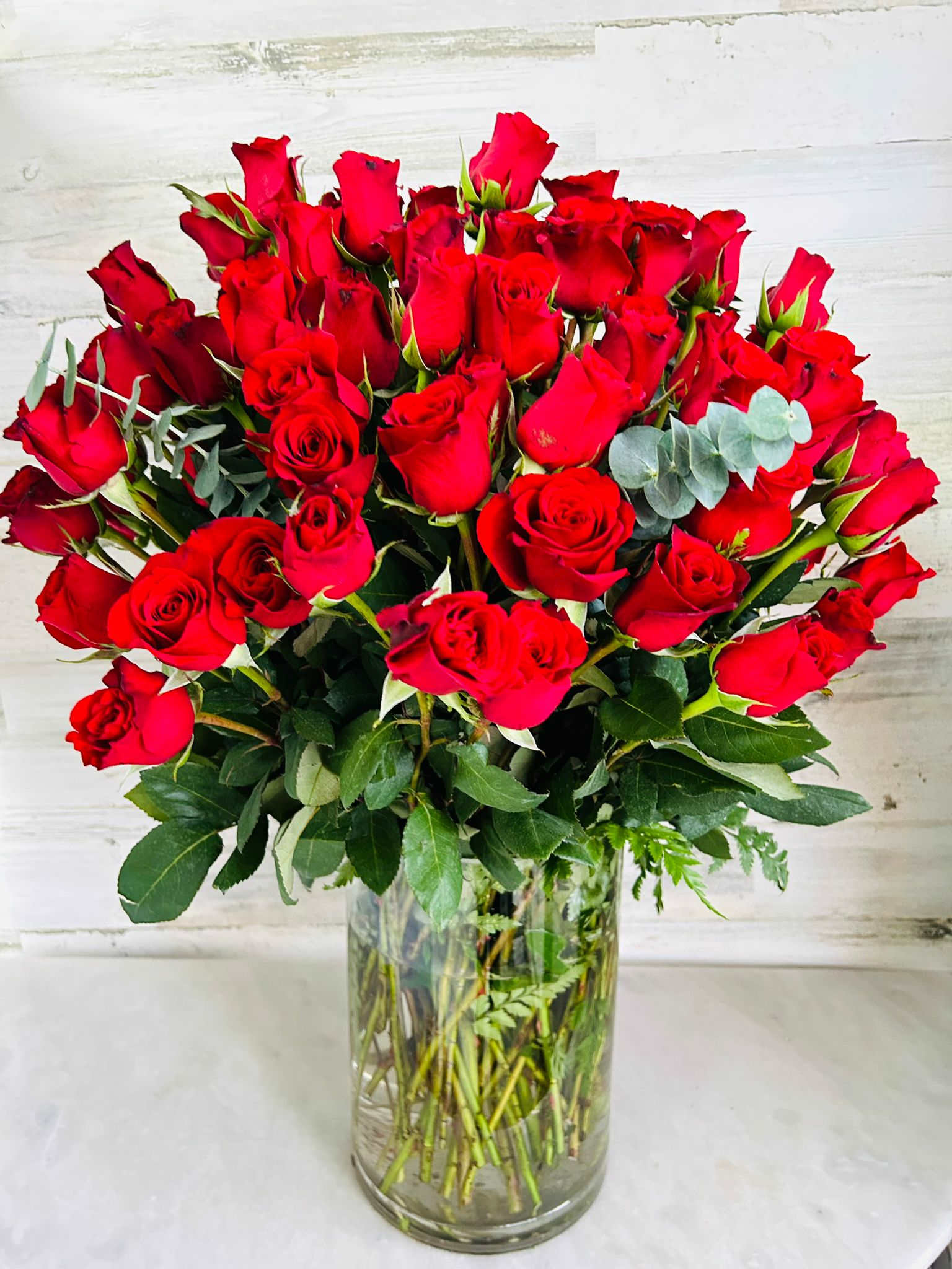 The Hundred The Hundred - 100 long stems red roses y a cylinder glass vase. Wants more? Deluxe version 112 roses, Premium version 124