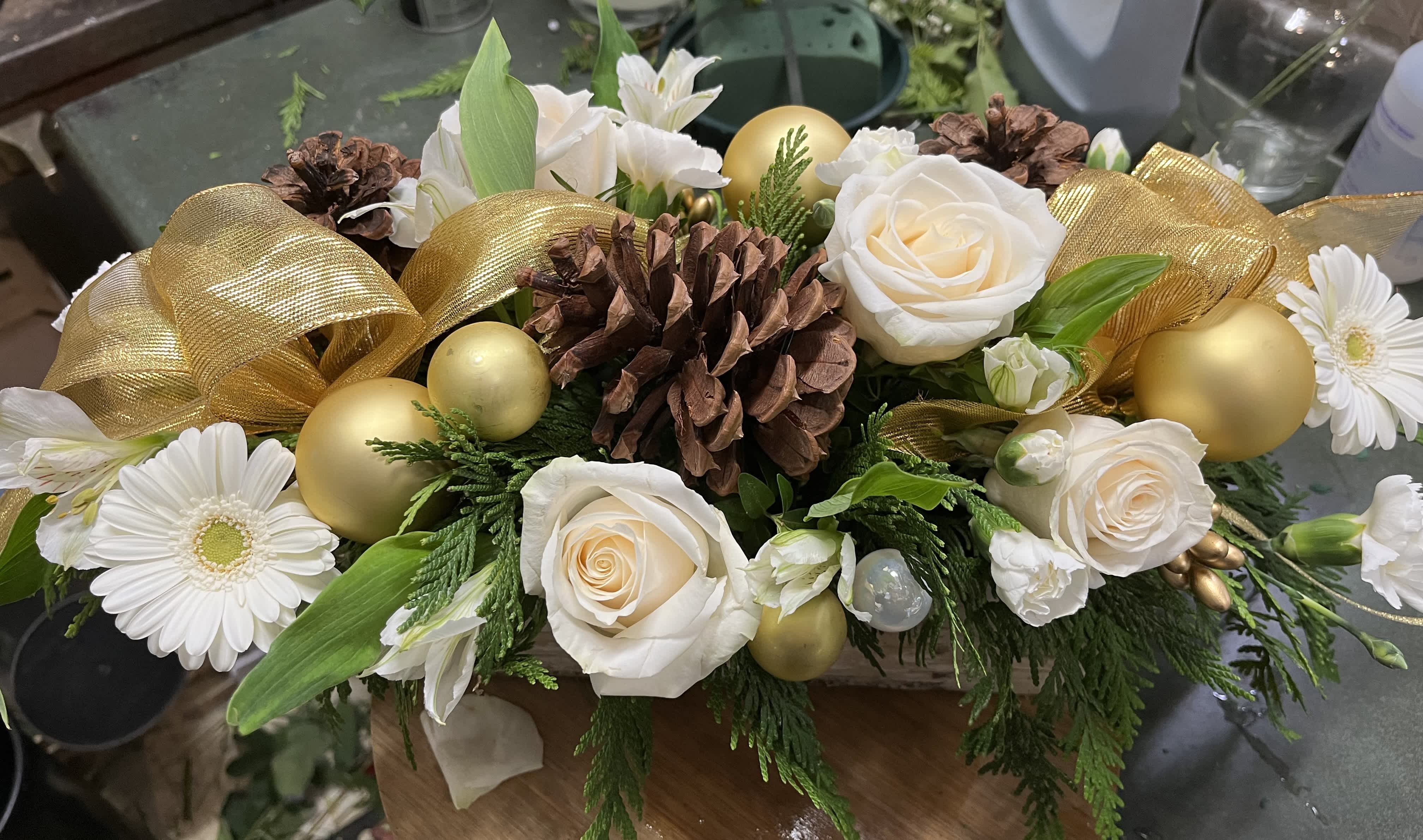 Touch of Gold - Centerpiece with roses, gerbera, glass balls, ribbon, seasonal greens, and pinecones 