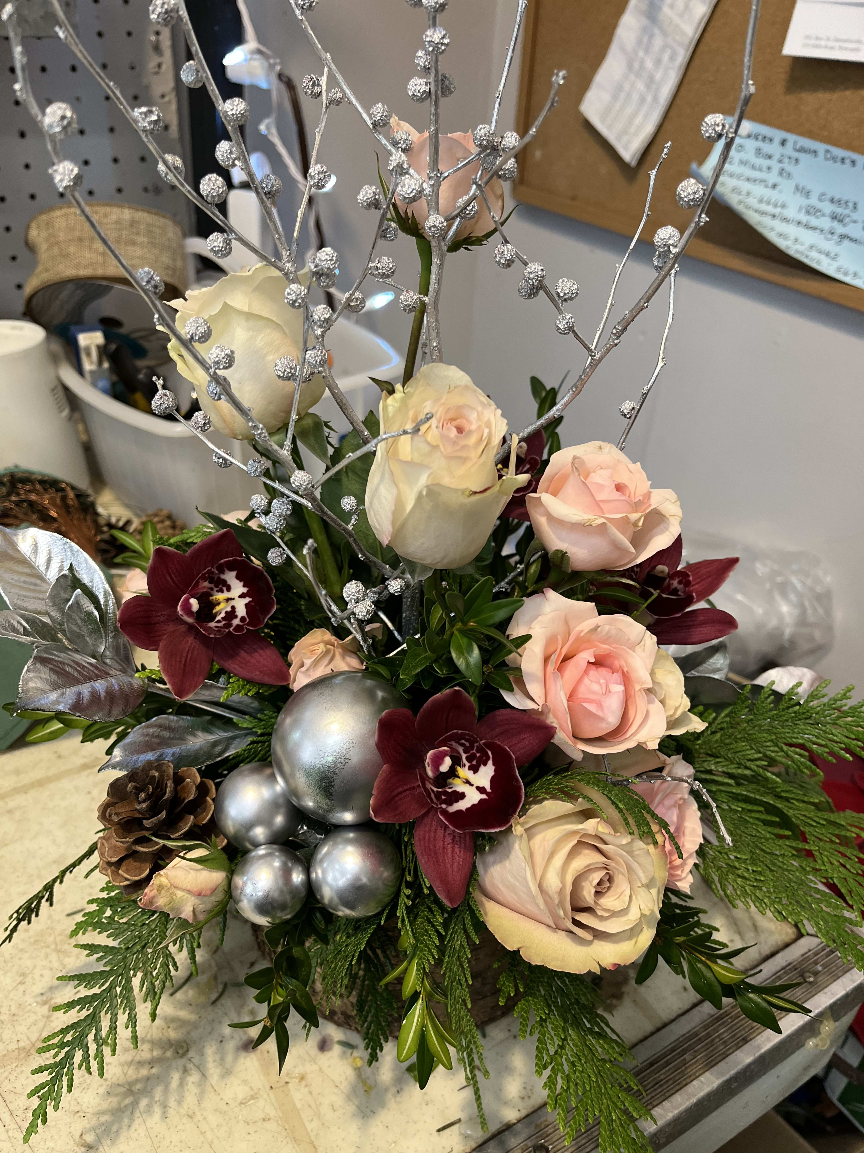 Winter Gumdrop  - Centerpiece arrangement with roses, orchids, seasonal greens and pinecones. 