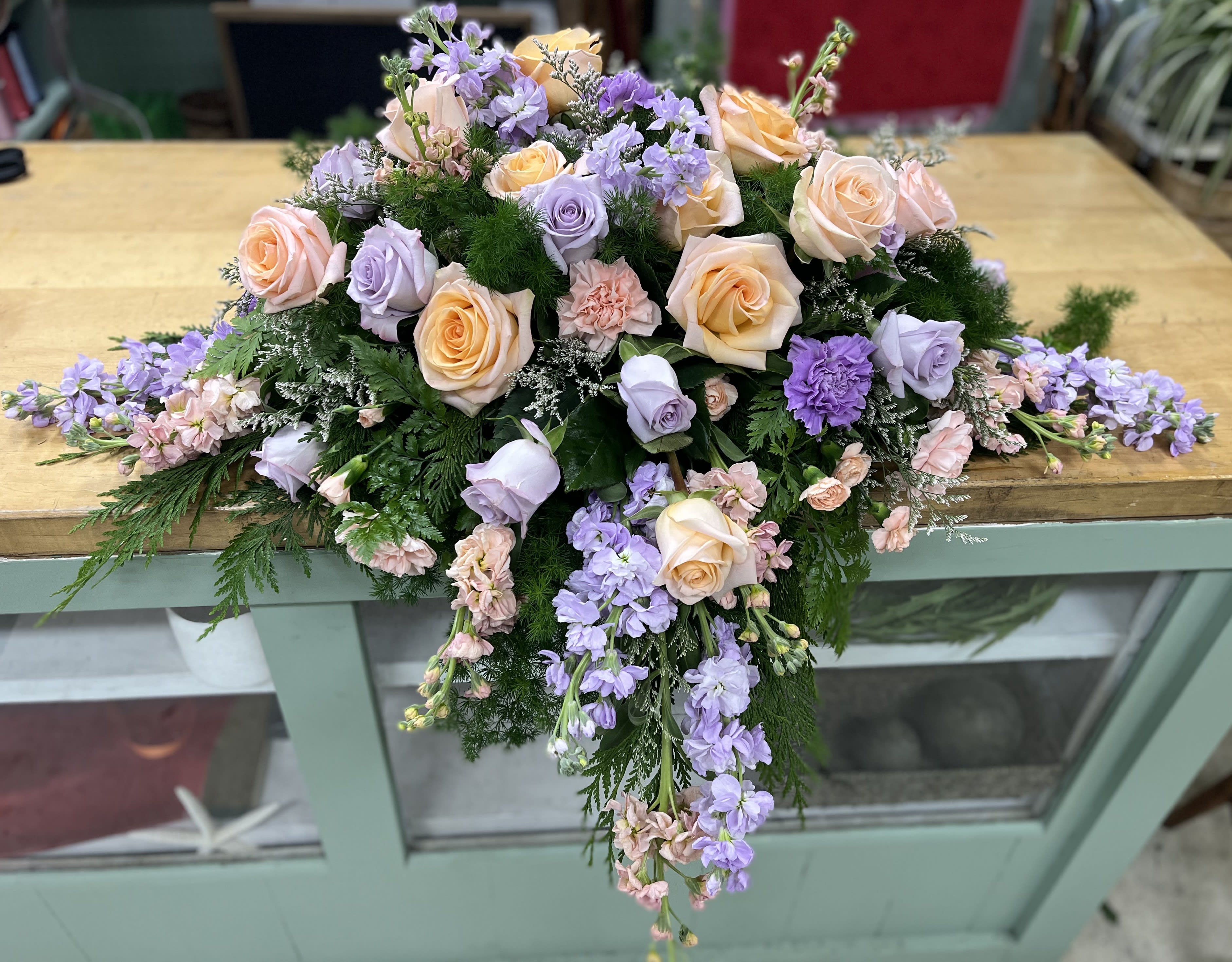 Unforgettable - Funeral spray made up with peach and lavender roses, carnations, and delphinium. 
