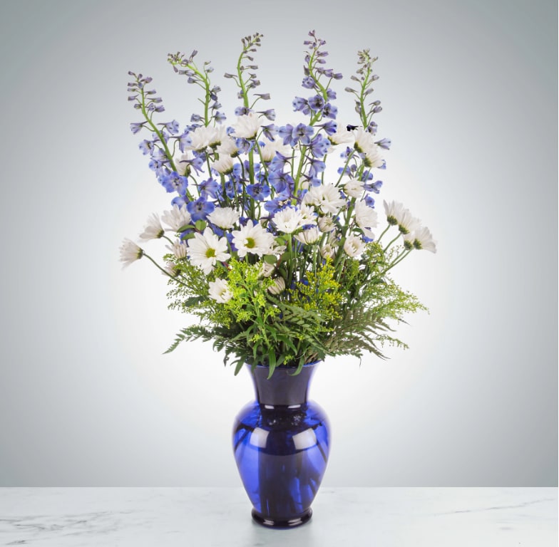Ahoy There by BloomNation™ - This tall blue and white arrangement is a breezy breath of summer air in an interesting vase. Featuring goldenrod, delphinium, and white daisy poms this arrangement is a sweet summer gesture. Send it for birthdays or as a just-because surprise.  Approximate Dimensions: 18&quot;D X 32&quot;H
