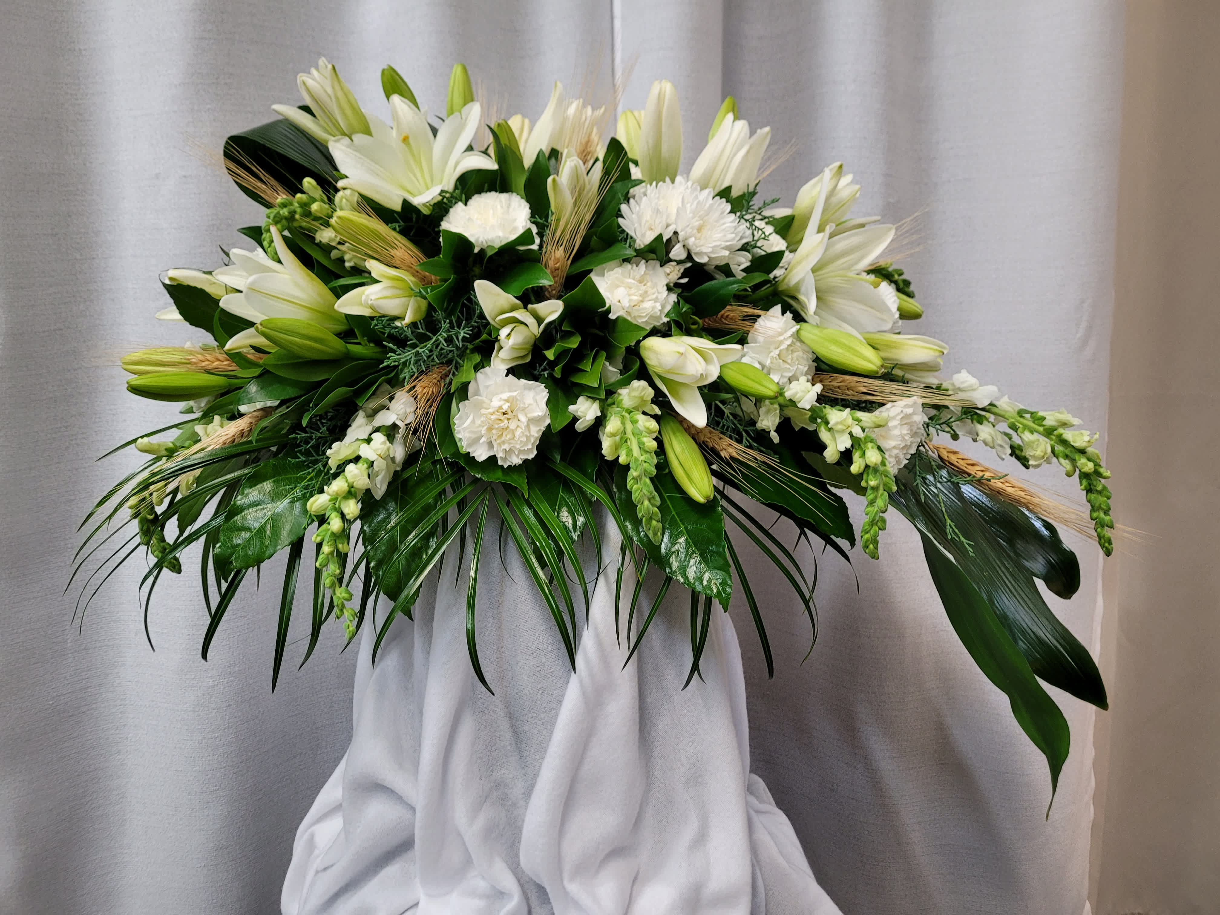 Wonderful White Casket Spray - This modern styled casket spray is 36&quot; in length. It contains snapdragons, asiatic lilies,  carnations and wheat.