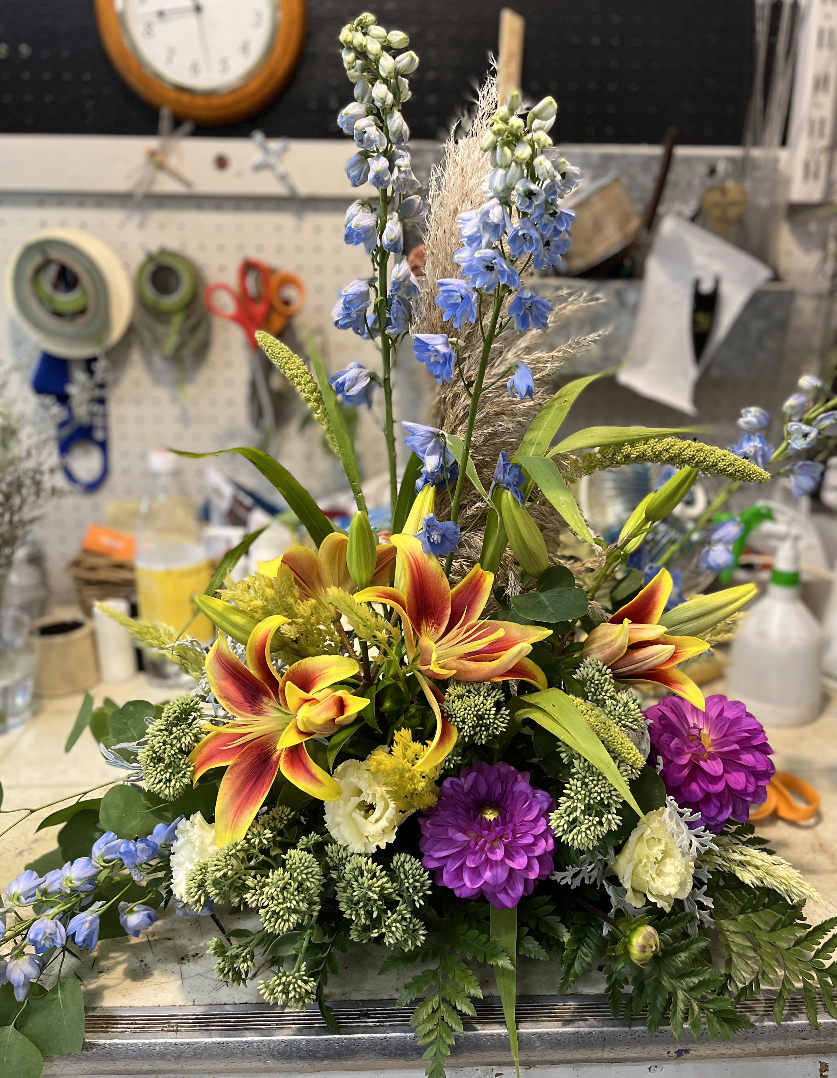 Smooth Sailing - Delphinium, seasonal lilies, dahlias, and lisianthus in a low dish. 