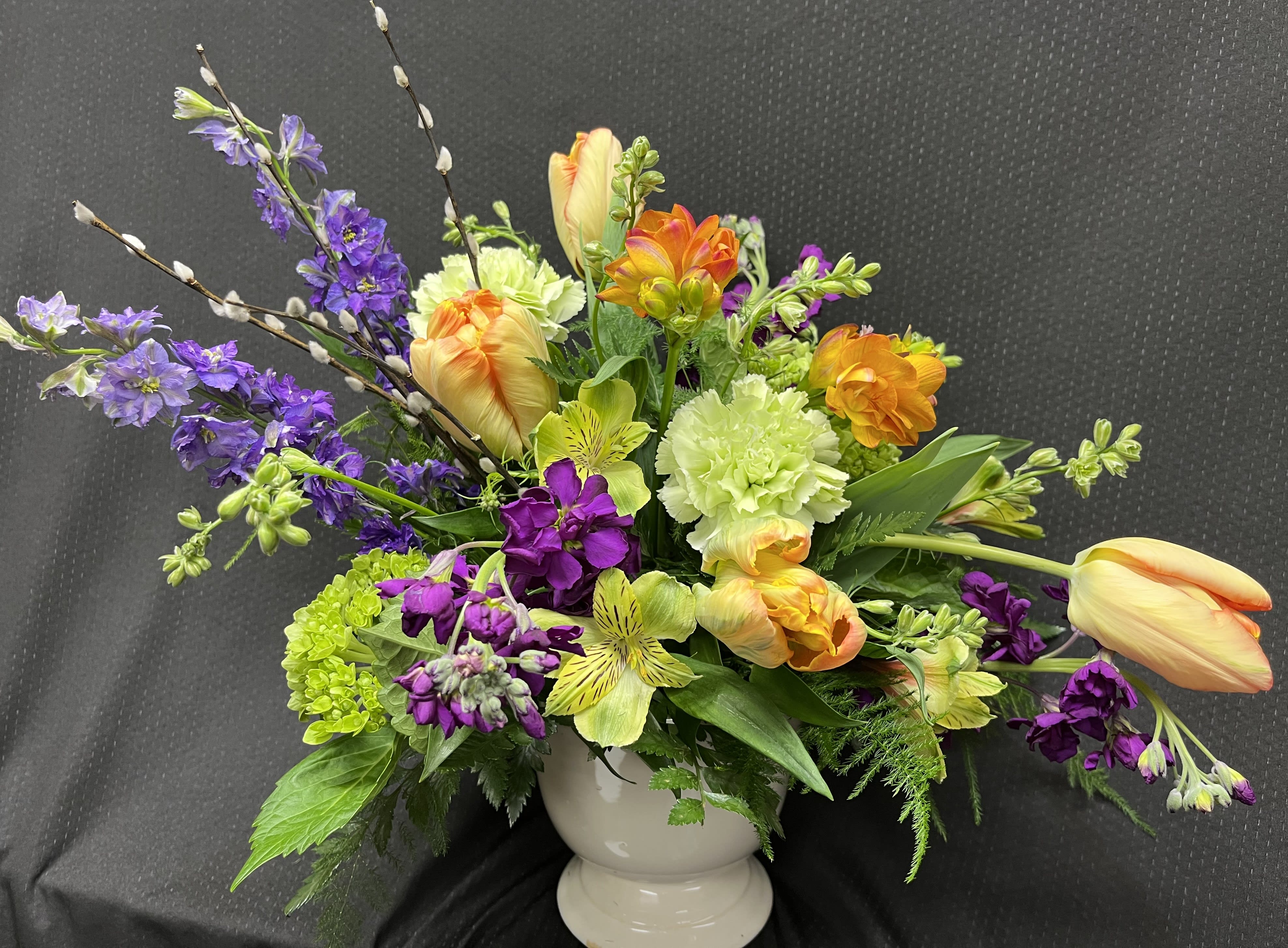 Spring feel - beautiful spring arrangement made up of tulips, stock, carnations, larkspur, and pussy willow in compote vase. 