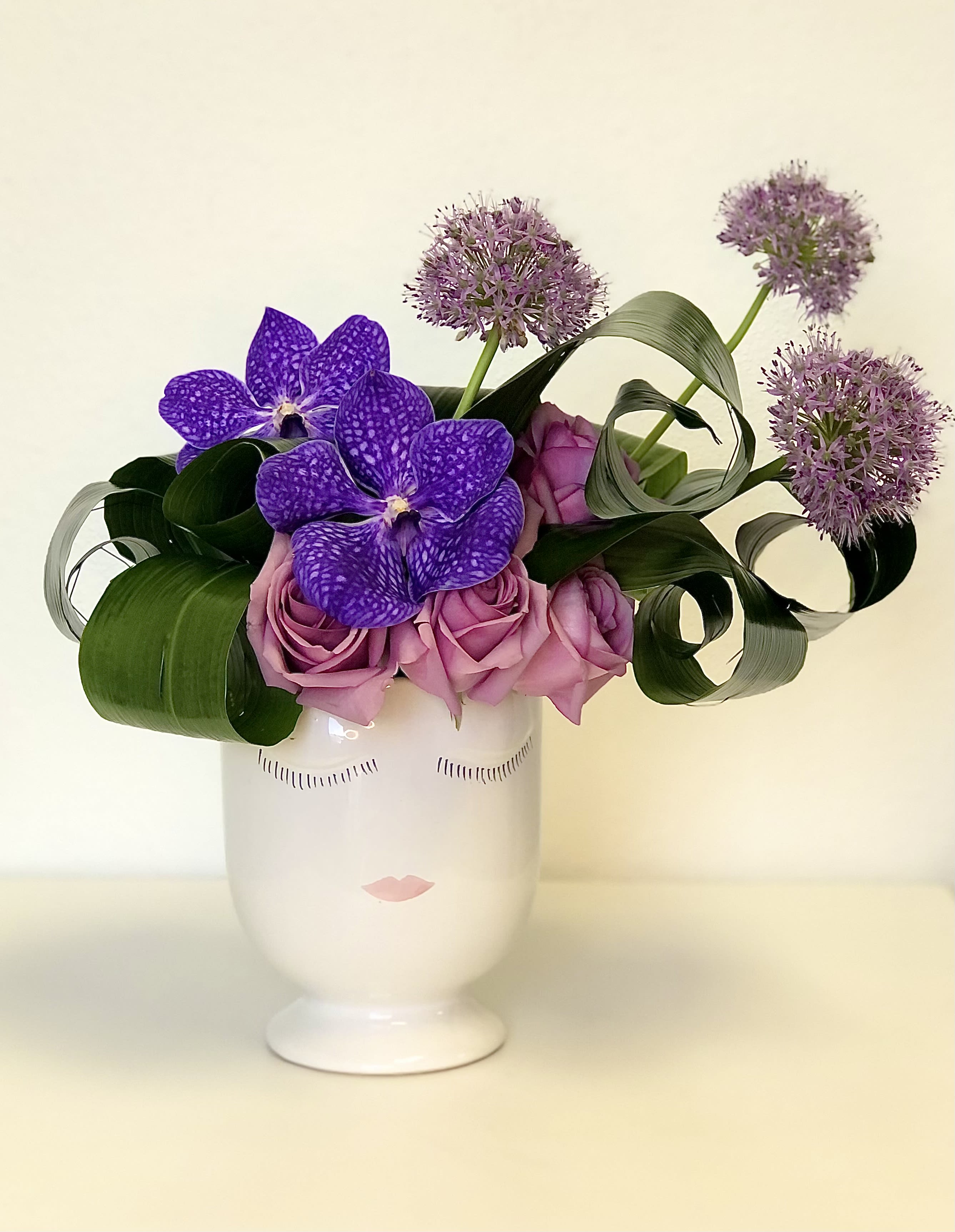 Halle - This manicured floral hairstyle is made with allium, spray roses, roses, and accented with purple vibrant vanda orchids – showcased in our selfie pot.