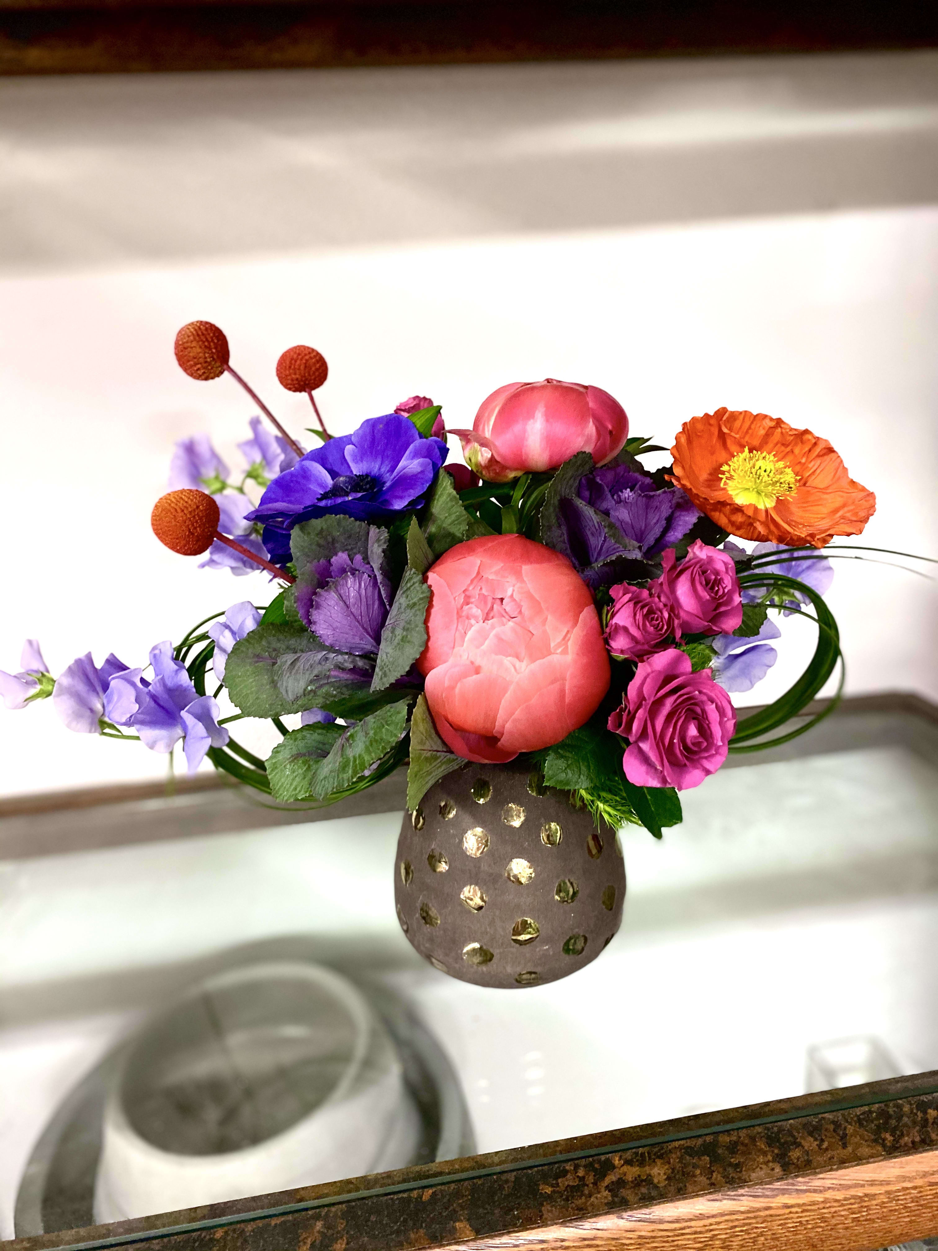 Charolette  - This flirtatious and colorful arrangement is made with the ever-so-loveable coral peonies, purple kale, lavender sweet peas, blue anemones, and finished off with dyed billy balls. Sure to be a hit with the fun-loving and playful person in your life. 