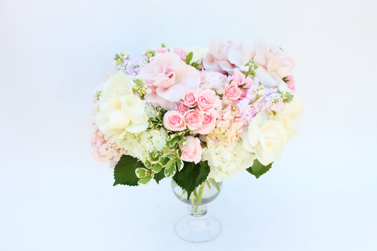 Romantic Pastel - Lovely array of pastel colors with roses, stocks, and greenery in a unique glass vase