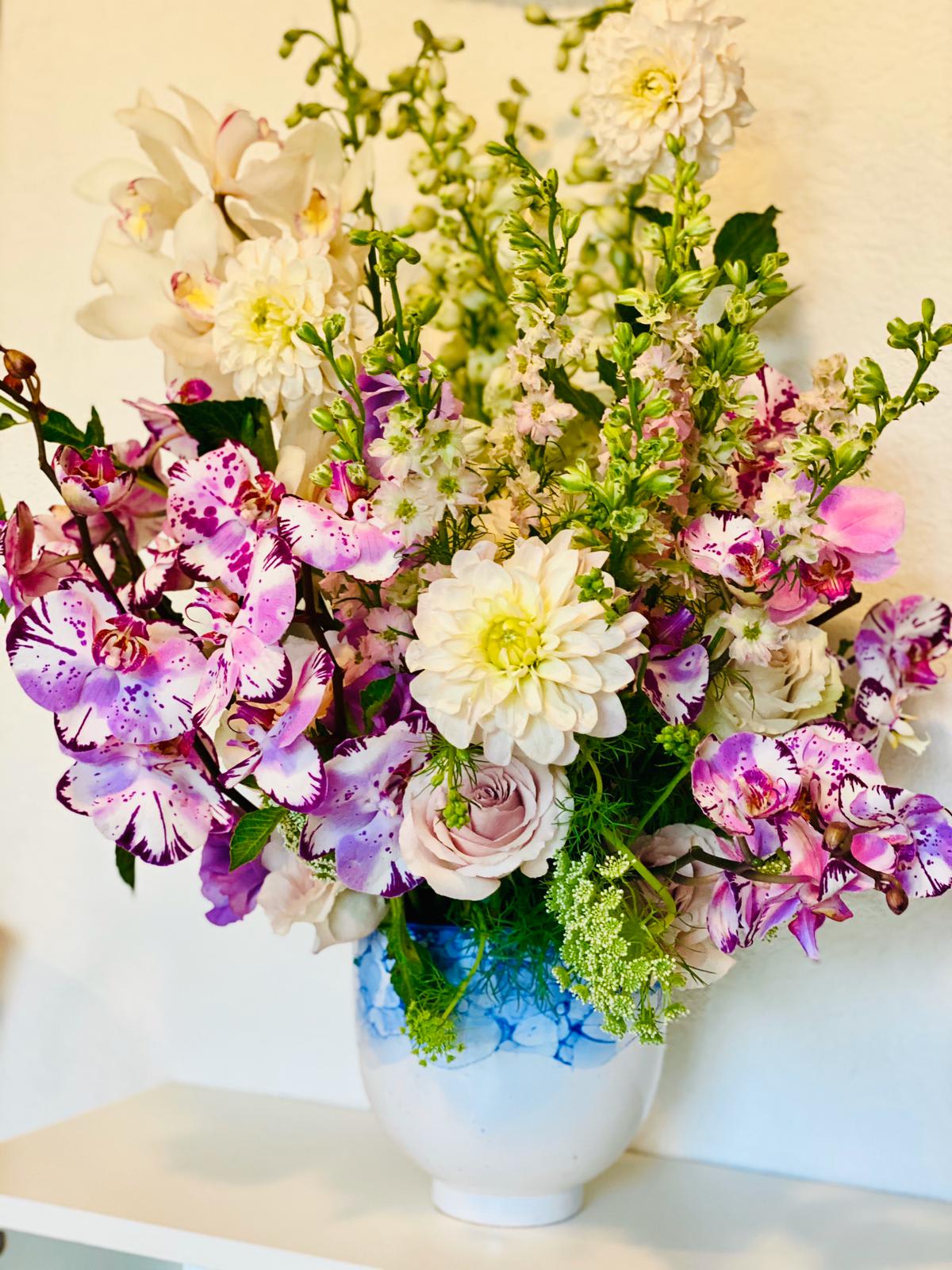 Whimsical Garden - Like a mini English garden, this charming arrangement features a whimsical cluster of cheerful florals and greens. Flowers may include orchids, larkspurs, dahlias, roses, and Queens Anne's lace.  Please note that Aquafuzion prides itself on its green thumb, and there may be substitutions depending on seasonal availability.