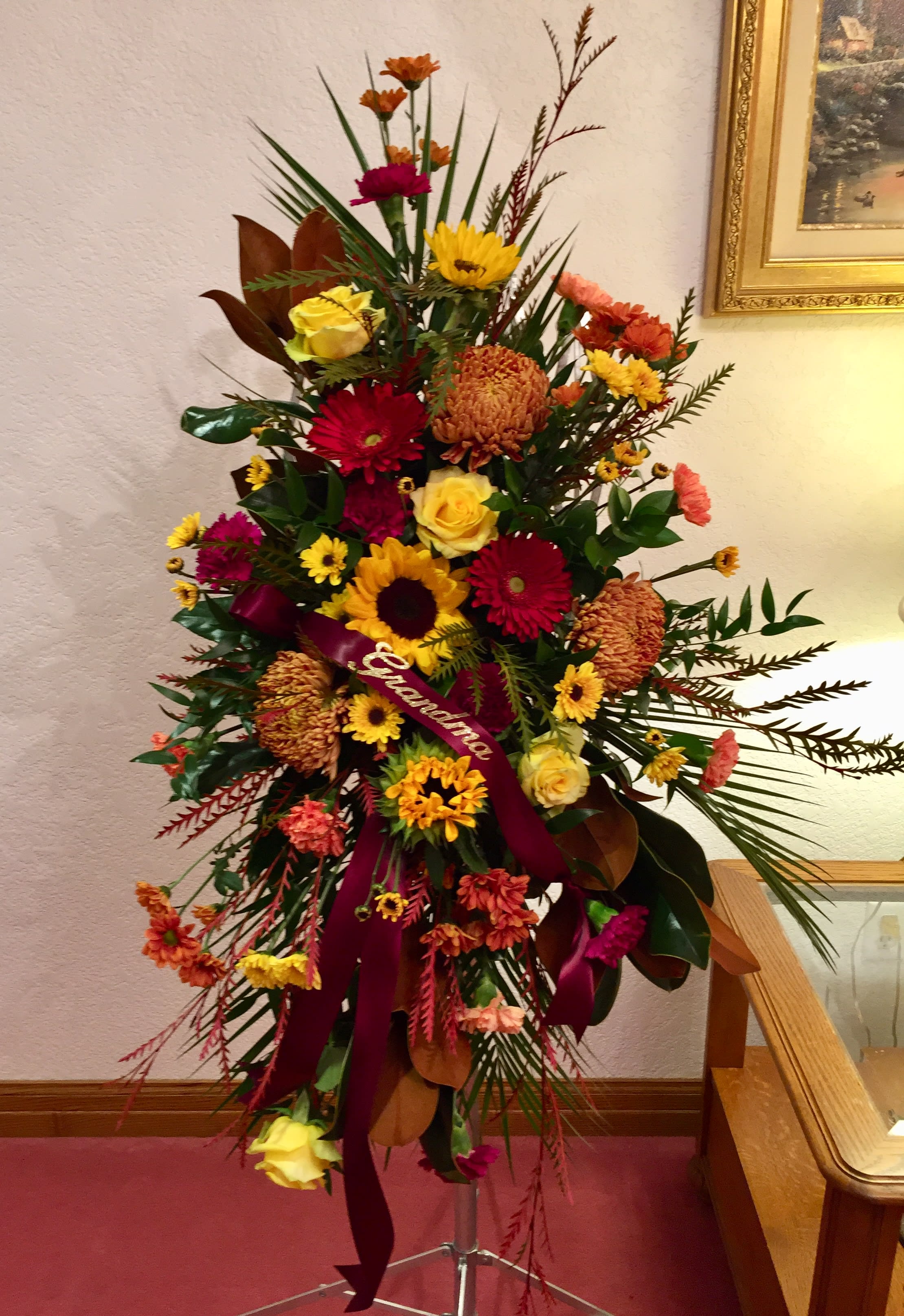 Standing Easel Spray Standing Easel Spray - Mixed garden spray with yellow roses, autumn mums, magnolia and burgundy carnations.