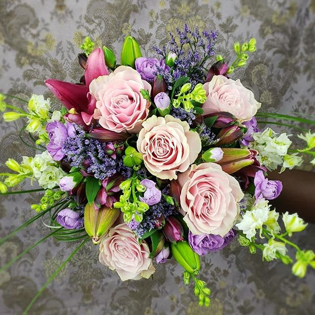 Purple Blush Wrapped Valentine Bouquet - Adorn her  with this Purple, Blush and Rose, delphiniums, Alstroemeria, Lilies and foliage.  Wrapped in color cylo and with a Bow for added pop *Each bouquet can be modified to fit brides color palette. Some flowers may be substituted do to some flowers are seasonal.