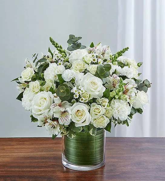 Cherished Memories - All White - Product ID: 95379   Send a gift of lasting tribute and touching remembrance of a life well lived. This striking, all-white arrangement of roses, spray roses, snapdragons, alstroemeria, carnations and more, elegantly arranged by hand in a graceful cylinder vase. A lovely gift of comfort and honor. Fresh arrangement of white roses, spray roses, snapdragons, alstroemeria, carnations, mini carnations, and monte casino, gathered with variegated pittosporum and spiral eucalyptus Hand-designed by our expert florists in a stylish clear glass cylinder vase wrapped with a Ti leaf ribbon; vase measures 6&quot;H Appropriate for the service or for sending to the home of friends and family members Large arrangement measures approximately 16&quot;H x 17&quot;L Medium arrangement measures approximately 15&quot;H x 16&quot;L Small arrangement measures approximately 14&quot;H X 15&quot;L Our florists hand-design each arrangement, so colors, varieties, and vase may vary due to local availability