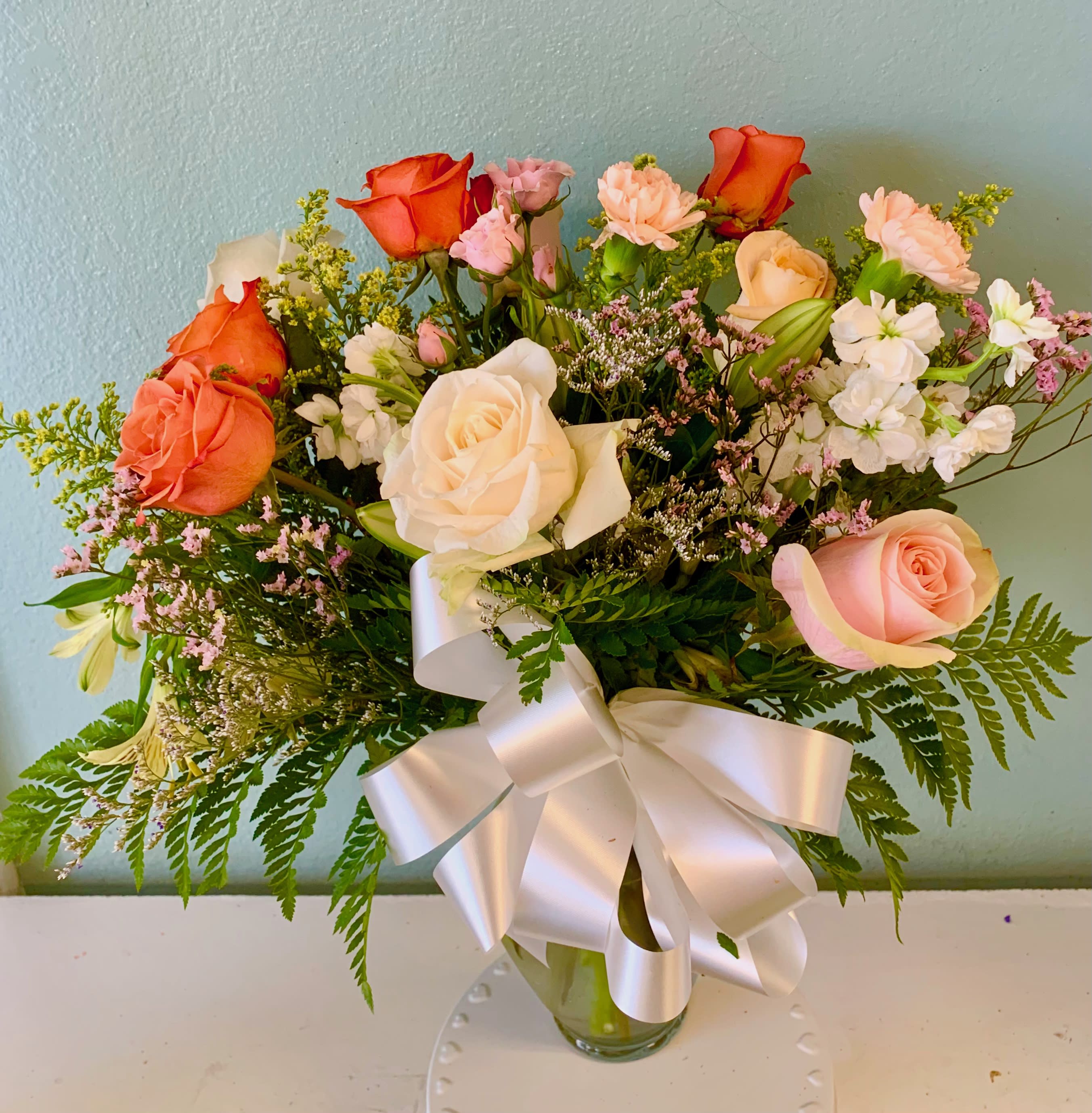 The Mary-Lucy Connection - Celebrating the JOY that brings people together! Featuring White, Peach and Orange Crush Roses, Solidago, Mini Carnations, Pink Limonium, Lively Stock, Lilies, greened with Leatherleaf, and finished with an elegant bow.