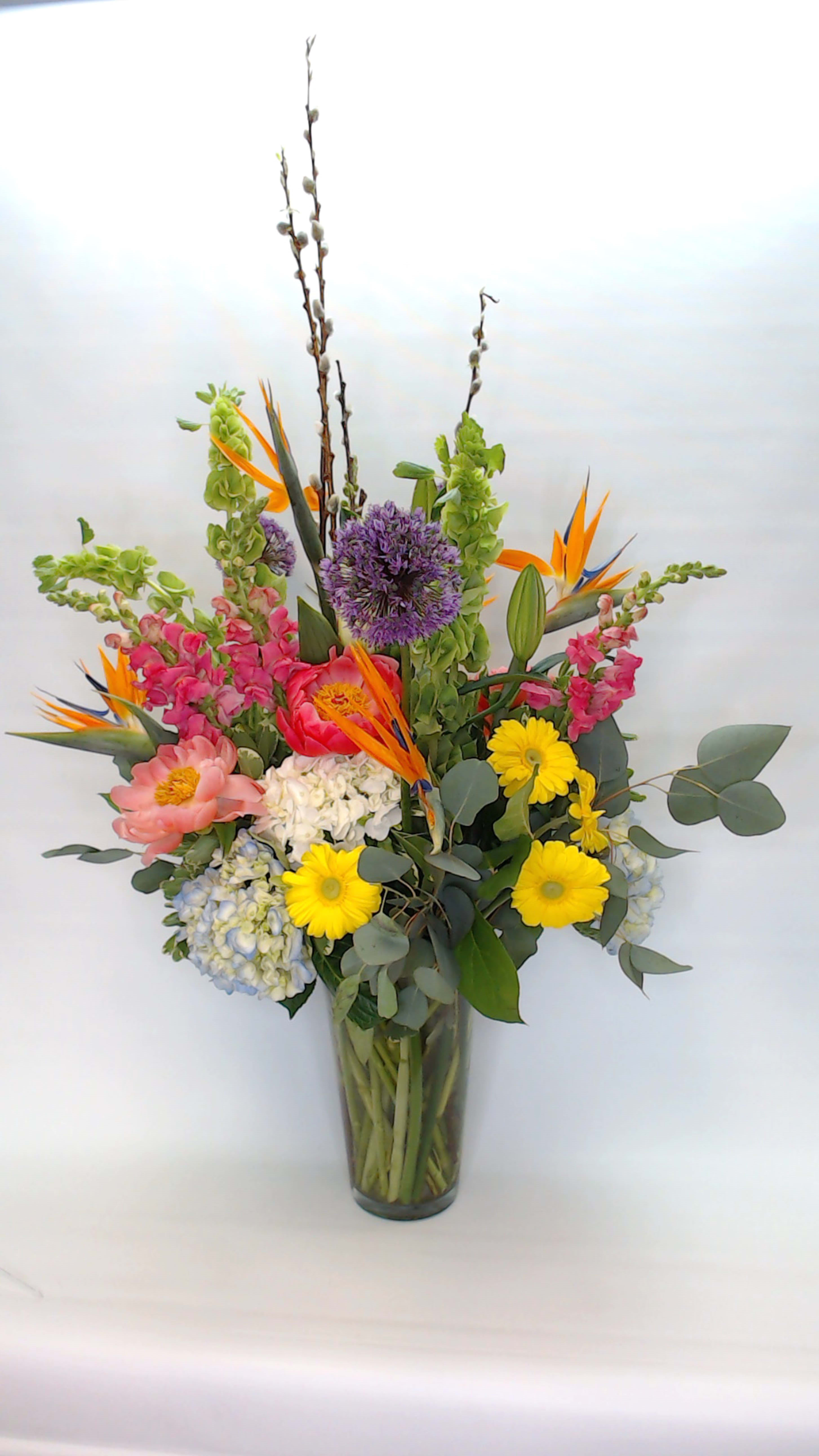 Spring into summer - A simple statement highlighting all the garden favorites. Gerbera daisies, hydrangea, roses, peonies, globe allium, birds of paradise. (Season may affect some flower availability) 