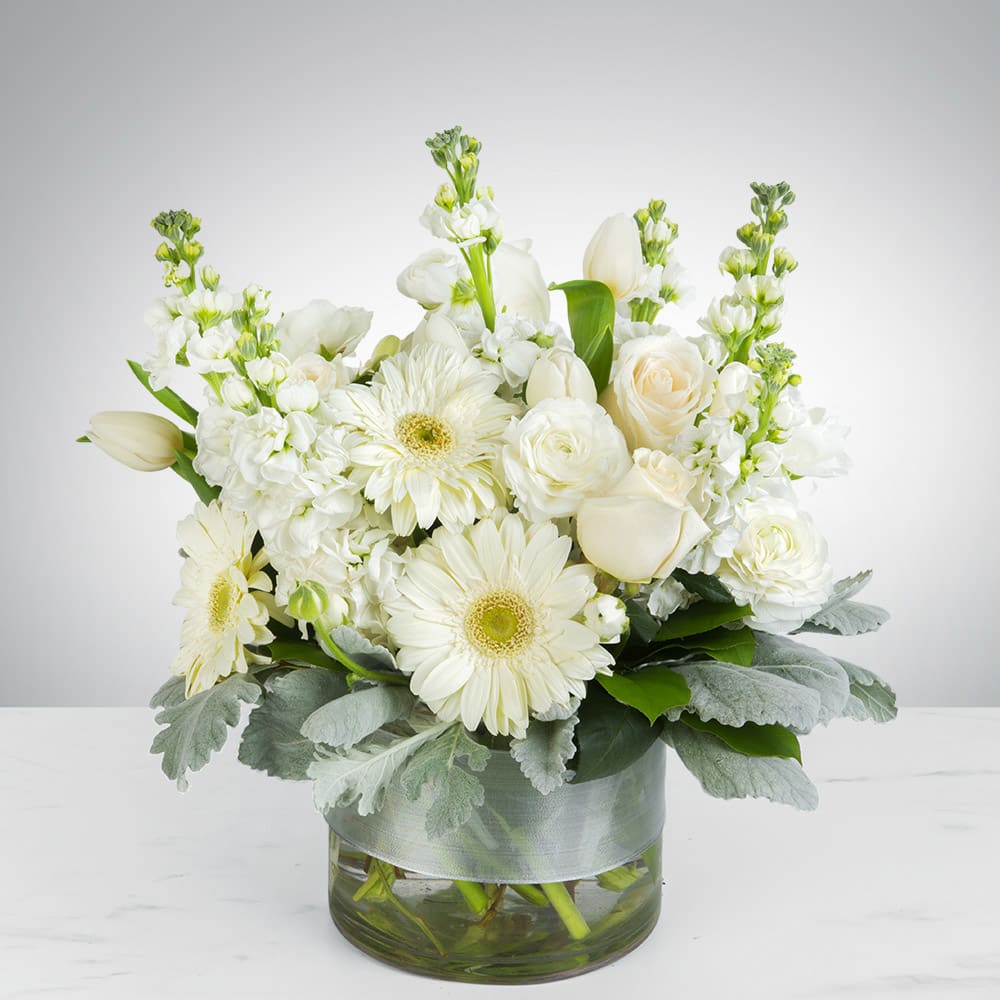 Purity  - This arrangement contains gerbera daisies, roses, tulips, stock, and other seasonal blooms. 