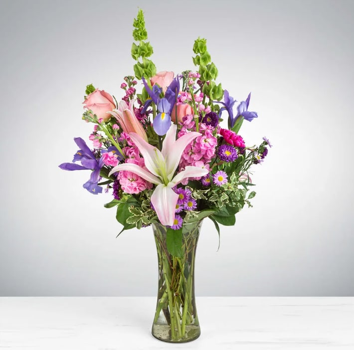 Enchanted Fairytale by BloomNation™ Enchanted Fairytale by BloomNation™ - This arrangement contains stargazer lilies, bells of ireland, stock, blue iris, roses, carnations, and purple aster. This is a great gift for birthday, Mother's Day, love and romance, or to say thank you. APPROXIMATE DIMENSIONS: 16" D x 26" H