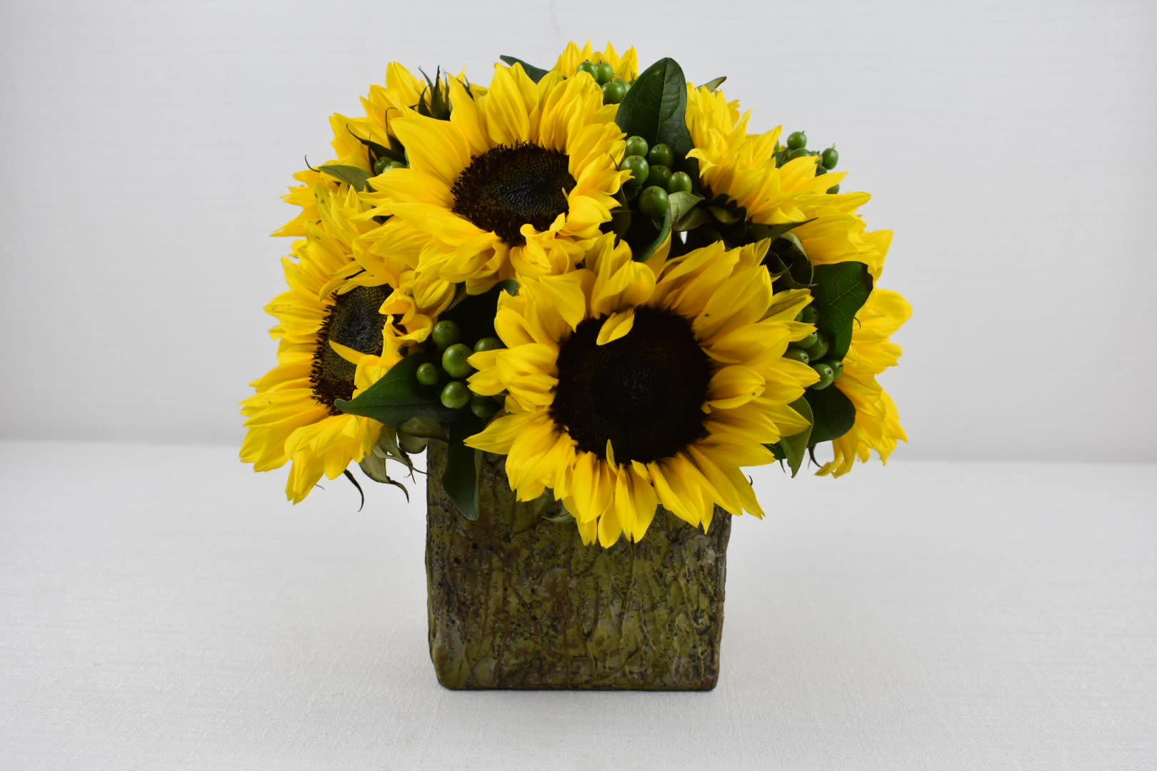 Sunny Flowers Sunny Flowers - Rustic Square vase 5X5 with some lovely sunflowers and a touch of green coffee bean A perfect arrangement for a just because surprise A good size for an office desk Perfect for birthday flowers anniversary flower just because flowers congratulations flowers Get well flowers Christmas flowers Valentines Day flowers Mother's Day flowers