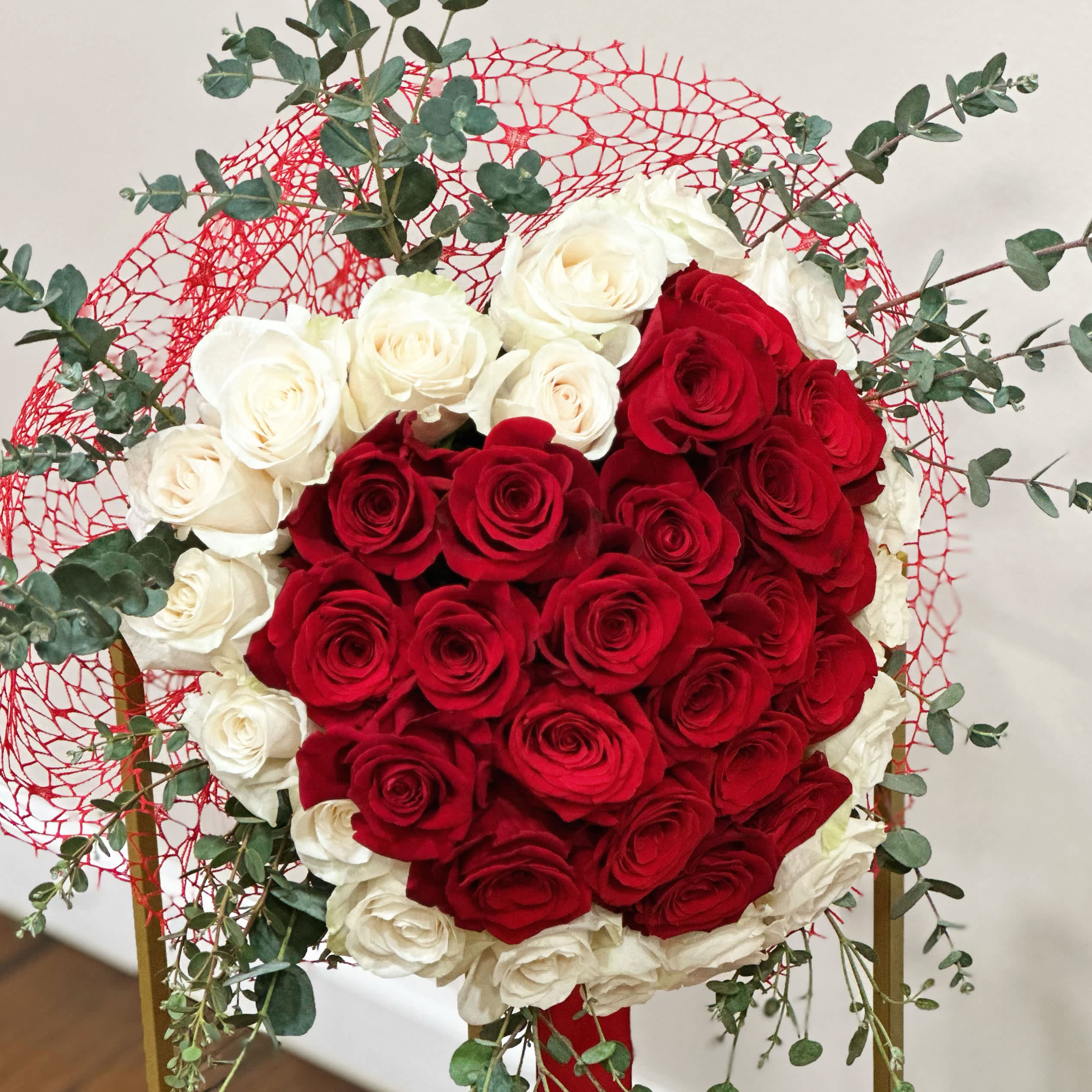Rose Heart Bouquet! - Red and White Rose Bouquet wrapped in a delicate red mesh and finished up with a beautiful satin ribbon. Smell of the spiral eucalyptus adds a fresh odor to the composition.  The shown bouquet has 21 white and 24 red roses!