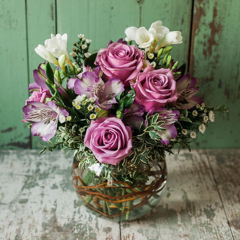 Jola Jola - A curly willow lined bubble bowl of purple roses with accent purple and white blooms. Approximately 10' tall x 9" wide #lebanonohioflorist #lebanonohio #sendflowers #celebrationflowers #sympathyflowers #masonohioflorist #masonohio #mainevilleohio #morrowohio #mainevilleohioflorist #morrowohioflorist #warrencountyohio #mothersday #mothersdayflowers #birthdayflowers #anniversaryflowers