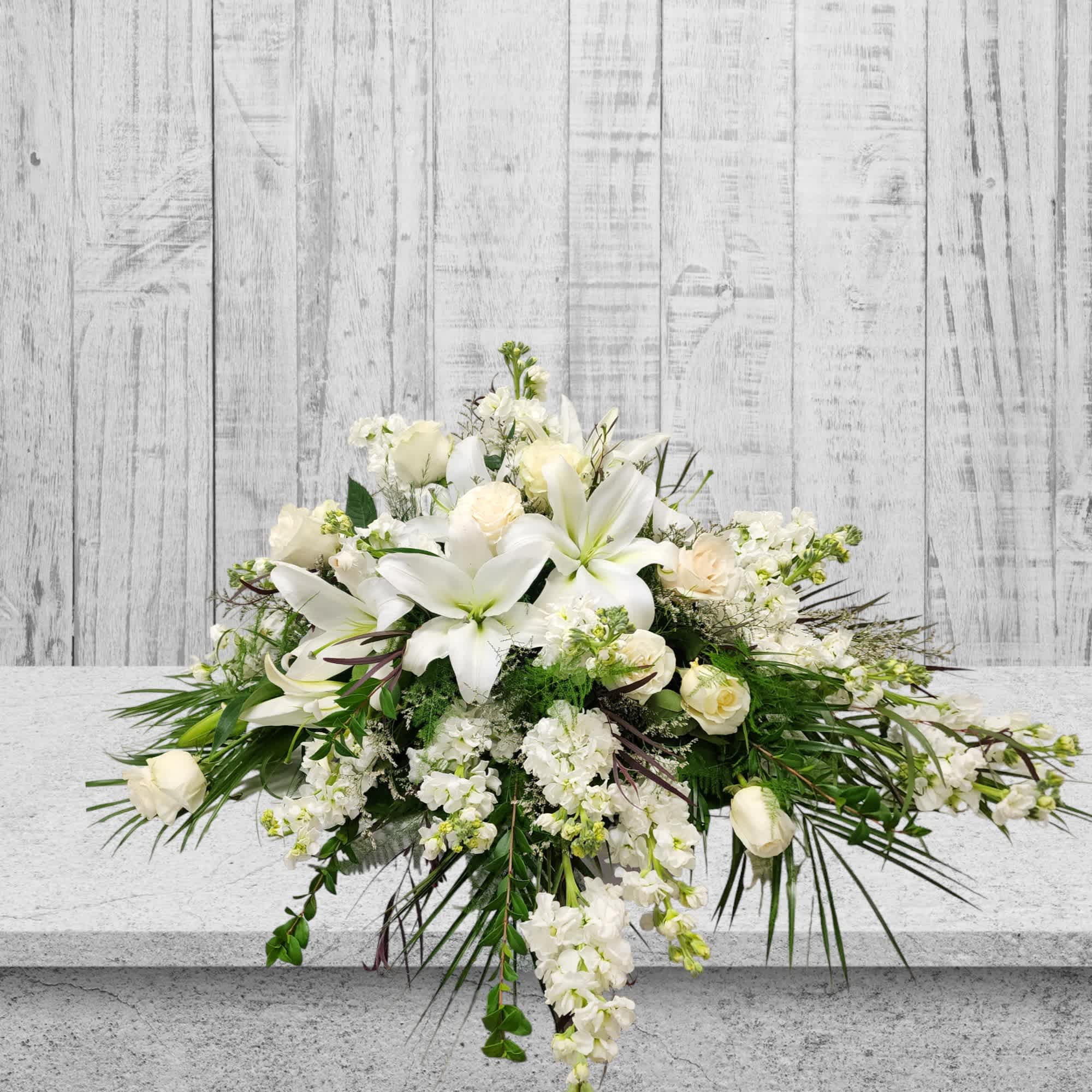 Lasting Memories Lasting Memories - Introducing Lasting Memories Casket Spray by Specialty Floral Design - Your Local Florist in Olympia, WA Elevate the tribute to your loved one with our exquisite Lasting Memorie Casket Spray, meticulously crafted by Specialty Floral Design. This specialty floral arrangement features a harmonious blend of pristine white lilies, delicate white roses, and fragrant white stock. Each bloom is carefully selected to create a symbolic representation that goes beyond words. The symbolism of Flowers: - White Lilies: Symbolizing the restored innocence of the soul, white lilies convey purity, virtue, and the essence of the departed's restored spirit. - White Roses: Representing reverence and love, white roses express eternal remembrance and serve as a beautiful tribute to the memory of your loved one. - White Stock: Signifying a lasting bond and a wish for a happy life, white stock adds a touch of fragrance to honor the cherished moments shared. Why Flowers for a Funeral Service: Flowers play a significant role in expressing emotions and offering comfort during difficult times. They serve as a visual expression of sympathy, love, and respect, providing a serene and peaceful atmosphere to commemorate the life of the departed. Coordinated Compassion: At Specialty Floral Design, we understand the importance of impeccable timing and thoughtful coordination during times of loss. In our commitment to providing compassionate support, we offer seamless coordination with esteemed funeral homes, including Mills and Mills Funeral Home, Woodlawn Funeral Home, and Funeral Alternatives. Our goal is to ensure prompt service, and effective communication, and to allow families the time they need before the funeral service. - Prompt Delivery: We work closely with funeral homes to synchronize delivery times, ensuring that your floral arrangements arrive punctually and in pristine condition. - Clear Communication: Specialty Floral Design prioritizes open and transparent communication. We liaise with funeral homes to keep you informed every step of the way, providing peace of mind during this challenging time. - Respectful Timing: Understanding the importance of allowing families time for reflection and preparation, we carefully coordinate with funeral homes to respect your schedule and preferences. When you choose Specialty Floral Design, you can trust that our dedicated team will go above and beyond to create a seamless experience. Our commitment to excellence extends to our collaboration with respected funeral homes, contributing to a dignified and heartfelt farewell for your loved one. Note on Lilies: Please be aware that lilies may require time to fully open and bloom. To ensure the optimal display, we recommend placing your order at least a week ahead of the funeral service. In case time constraints prevent the inclusion of lilies, Specialty Floral Design will thoughtfully substitute appropriate flowers to maintain the elegance and sentiment of the arrangement. At Specialty Floral Design, we understand the importance of creating meaningful tributes. Trust us to deliver beautiful floral arrangements with care and compassion. Order now to convey your deepest condolences and celebrate the enduring memories of your loved one. We offer prompt and considerate flower delivery services in Thurston County, Olympia, Tumwater, and Lacey, WA.