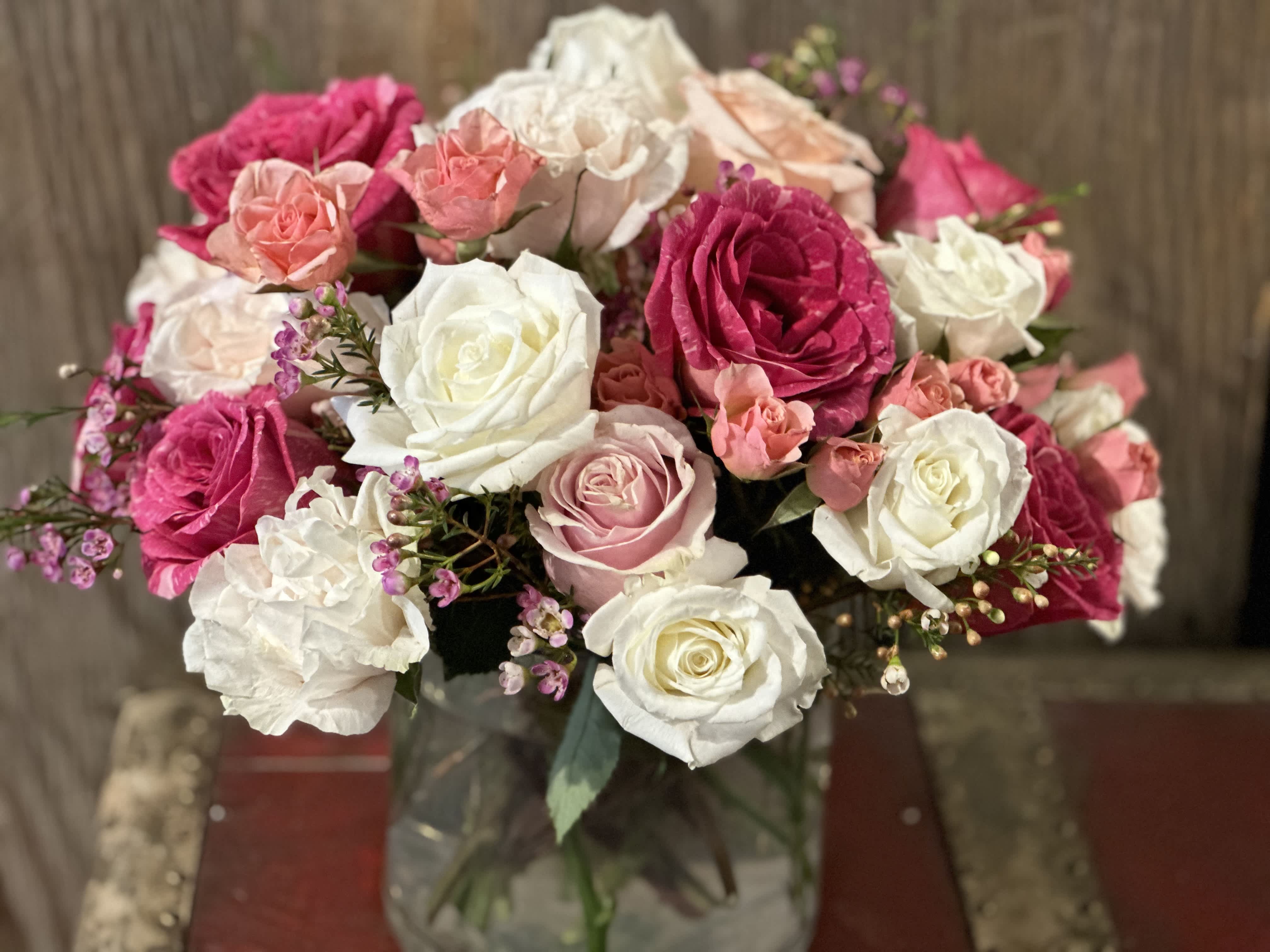 Love Struck - 18 lush roses arranged with a low and lush assortment of spray roses and wax flower. This beauty strikes a punch!