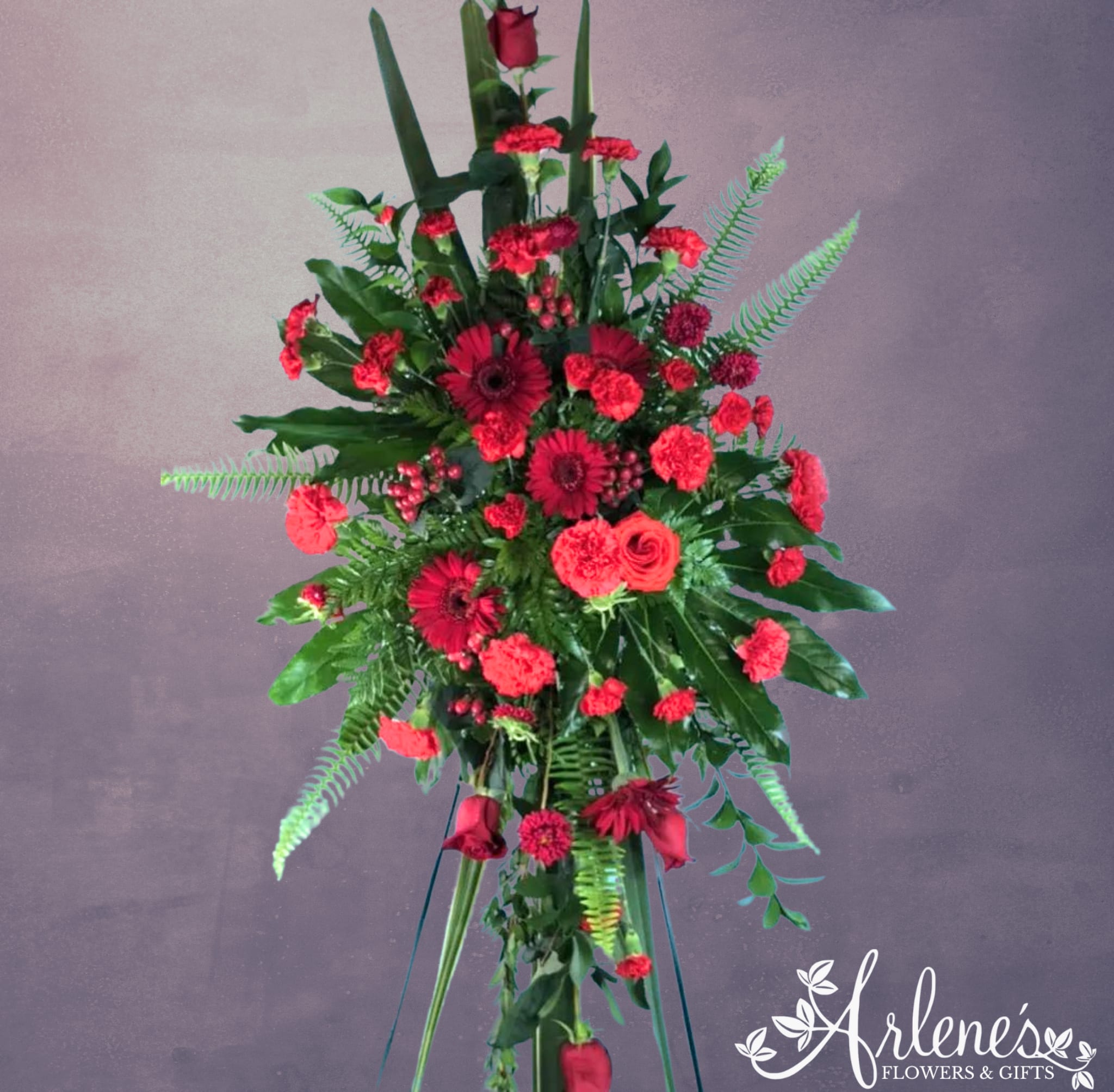 Red Spirit - Strong, vital and deeply moving, this all red sympathy spray stands to honor the loss of a loved one. It features upgraded and unusual greenery and a mix of red flowers (carnations, gerbera daisies and red roses).