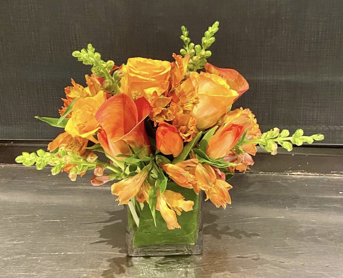 Custom arrangement of orange roses &amp; orange calla lilies - Custom arrangement of orange roses, orange calla lilies, orange tulips &amp; orange alstroemeria in clear glass cube.