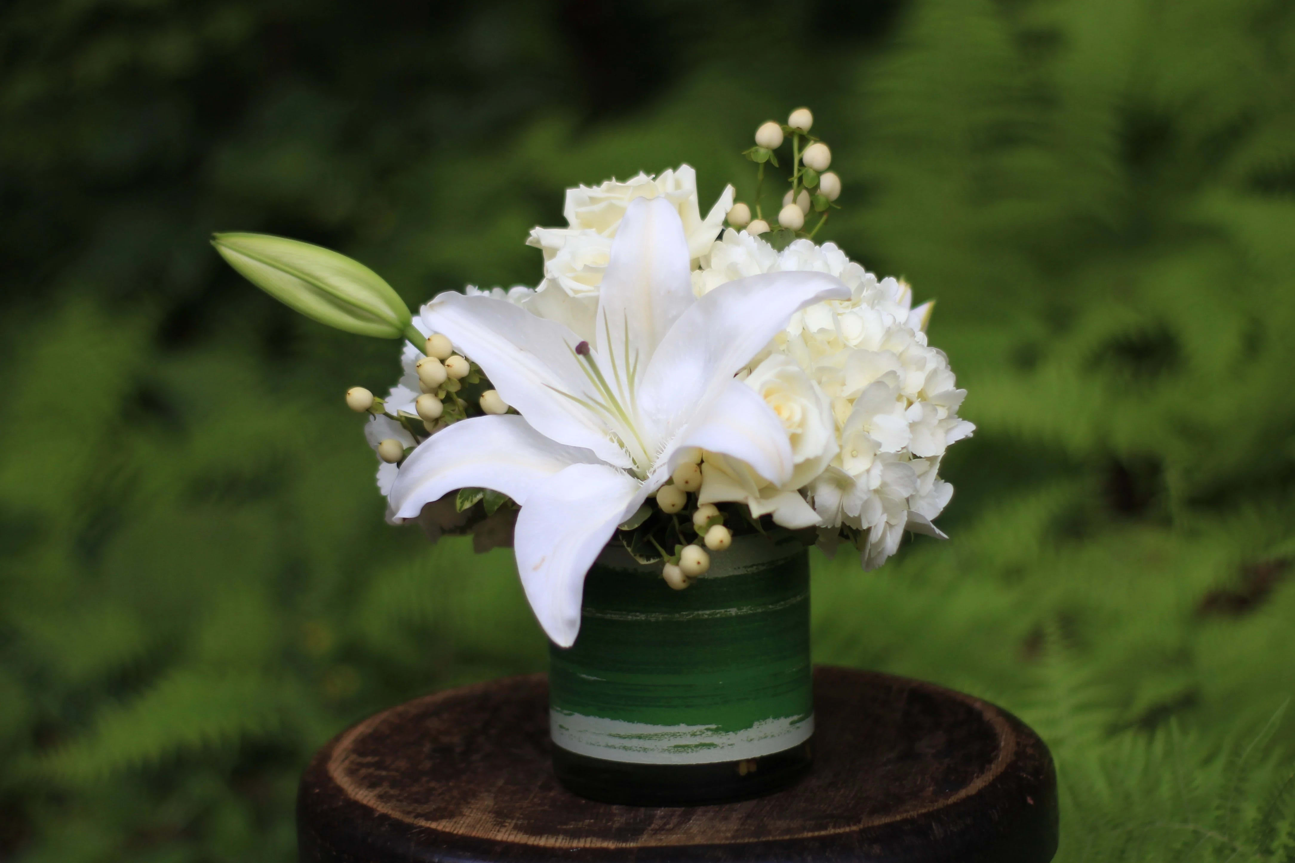 Creme De La Creme - Soothing creamy and white blooms arranged in a compact fashion in a leaf line glass cylinder vase. A lovely combination of premium grade white flowers with a hybrid white lily focal is sure to make a statement. This all white bouquet is lovely to send to a loved one, just because or for an anniversary. It's also very nice to send in lieu of sympathy. Upgrades include more blooms and a larger presentation. In some instances we will create a white and green cylinder based on our available inventory.