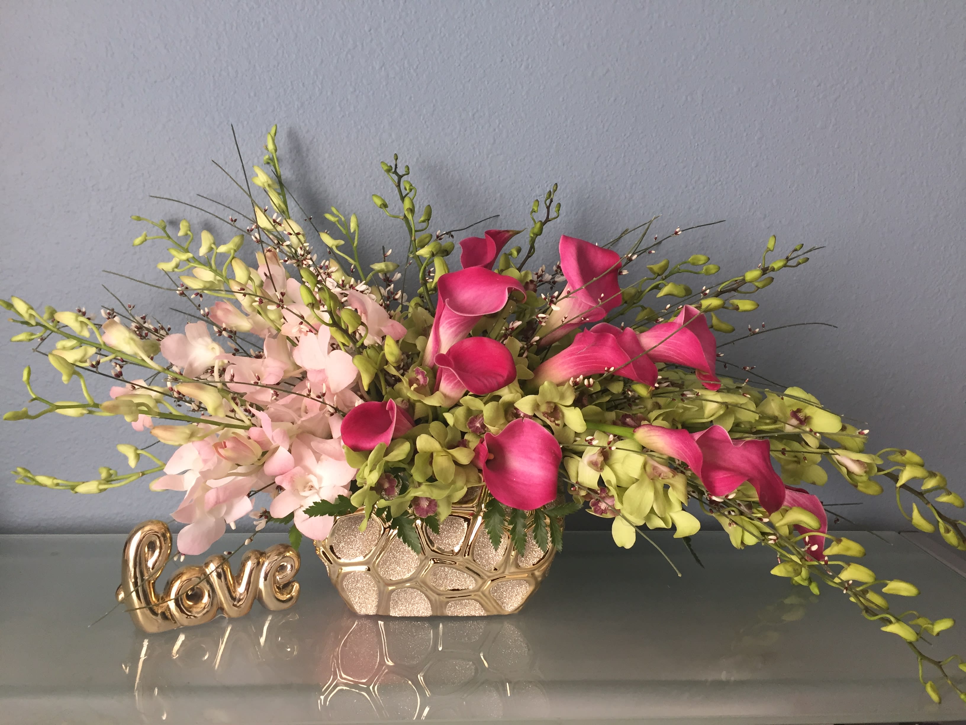 Ticket to paradise - As lush and serene as a tropical sunset, this paradise of feminine blooms is a unique way to send your best wishes. The well-balanced arrangement is both chic and Zen, with its graceful callas, dendrodium orchids and modern gold container.   •Light pink dendrobium orchids, light green dendrobium ochids, hot pink calla lilies are gorgeously gathered into a rectangular gold container. •Orientation: All Around 