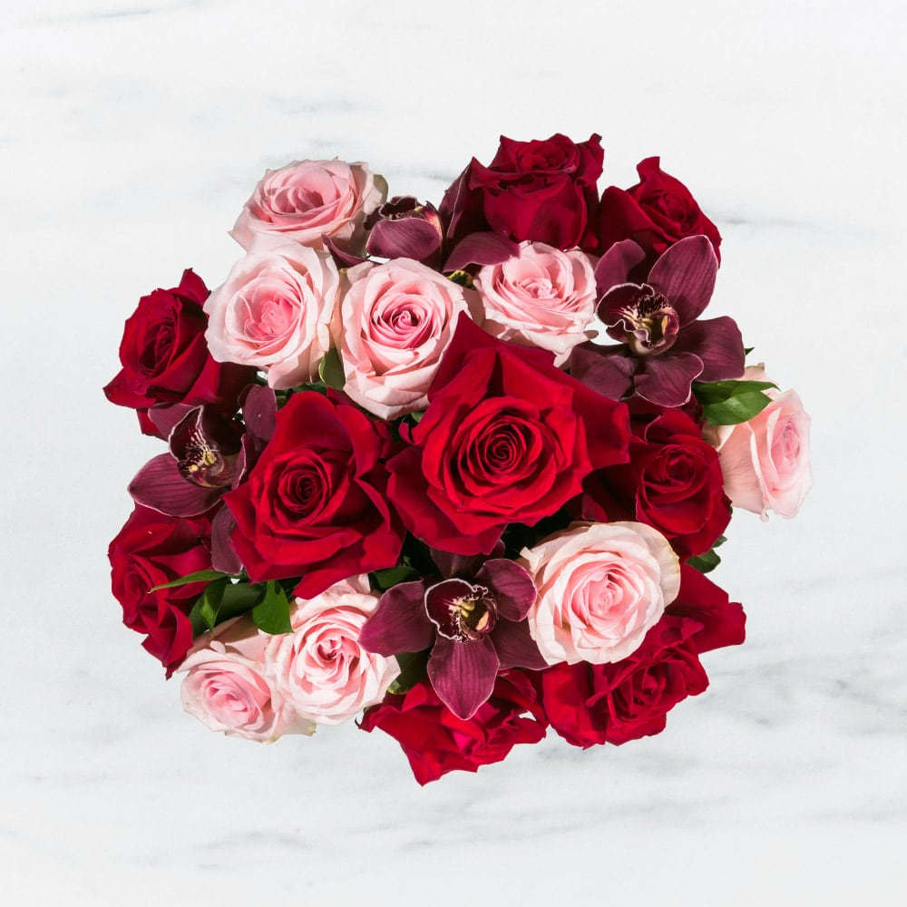 Truly Adored  - This arrangement includes purple cymbidium orchids, red roses, &amp; pink roses. Truly Adored is the romantic gift for Valentine's Day or Anniversary.   