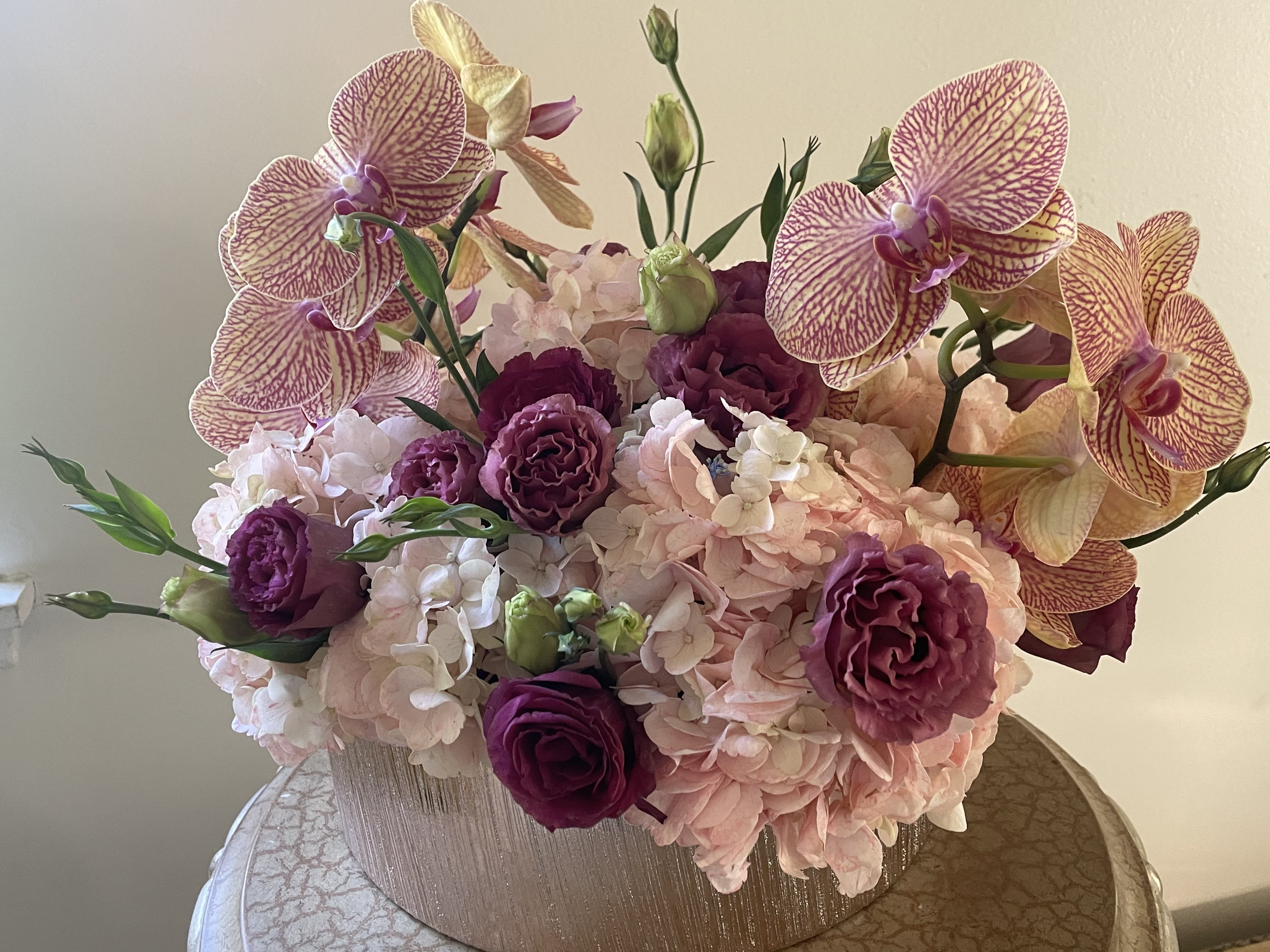 Peach Delight - Peach/ pinkish Hydrangeas, Purple lisianthus, orchids in rose gold ceramic vessel.
