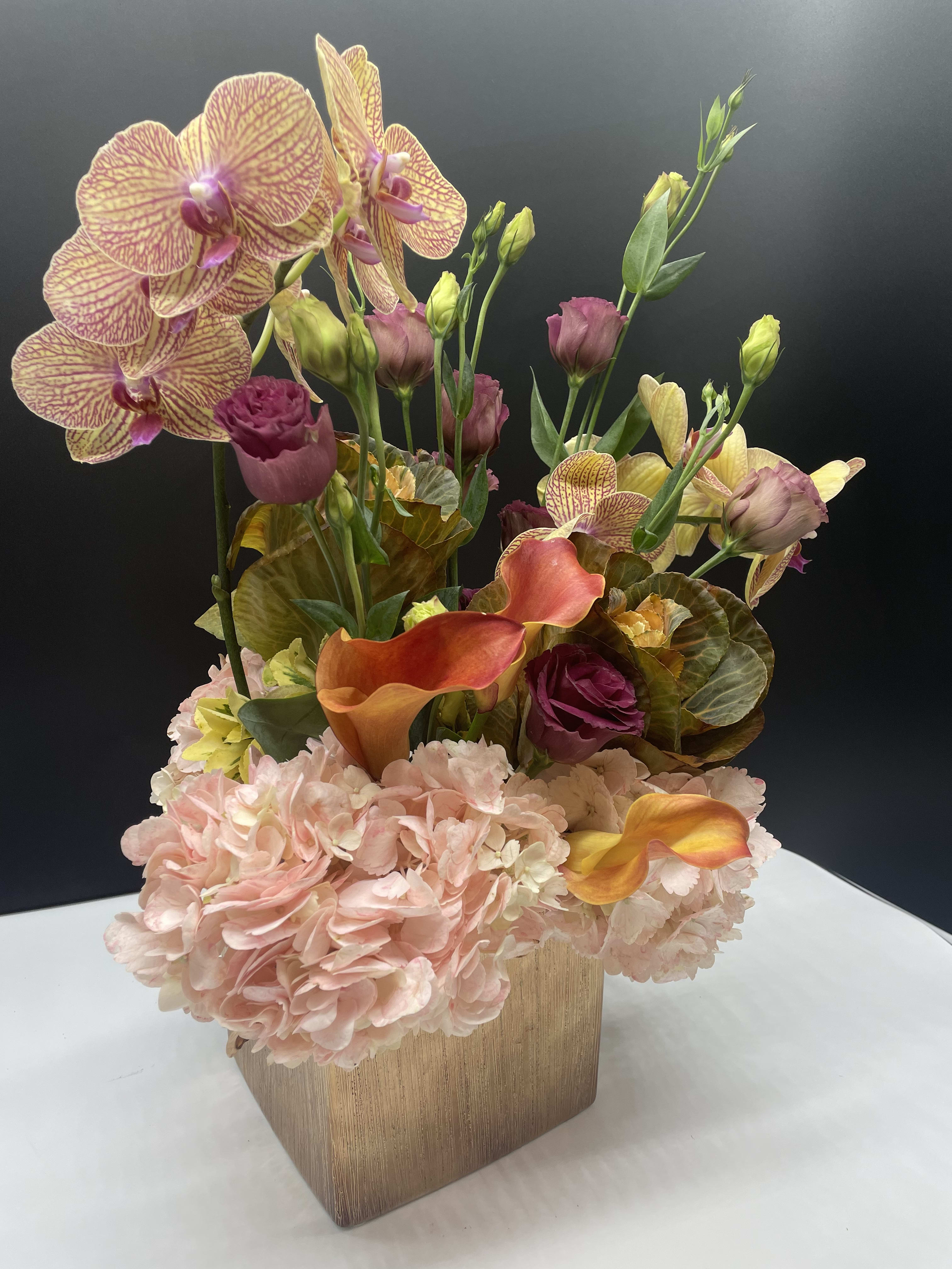 Peach &amp; Purple  - A combination of orchids, peach hydrangeas, mini calla lilies, lisianthus and cabbage in a rose gold ceramic vase. 