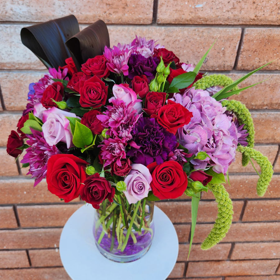 Amour Bouquet - A bold mix of jewel-toned flowers that is sure to make an unforgettable statement. Featuring premium roses, hydrangeas, carnations, spray chrysanthemums, red ti leaves - all hand arranged with fresh garden greens and delivered in a designer clear glass vase. Standard size is approximately 20in (W) x 24in (H). Deluxe and Premium versions are a little larger and feature more blooms.  Standard – 12 Red and Lavender Roses, 5 Red Spray Roses, 4 Purple Carnations, 2 Purple and Dark Pink Hydrangeas, 3 Spray Chrysanthemums &amp; Fresh Garden Greens - Glass Vase  Deluxe – 18 Red and Lavender Roses, 6 Red Spray Roses, 5 Purple Carnations, 2 Purple and Dark Pink Hydrangeas, 4 Spray Chrysanthemums &amp; Fresh Garden Greens - Glass Vase  Premium – 24 Red and Lavender Roses, 7 Red Spray Roses, 6 Purple Carnations, 3 Purple and Dark Pink Hydrangeas, 5 Spray Chrysanthemums &amp; Fresh Garden Greens - Glass Vase  Care Tips: Place your bouquet in a cool location. Don't put the arrangement in direct sunlight, near heating or cooling vents, in drafty places, directly under ceiling fans, or on top of televisions or radiators. Check water level daily, keep the vase full with clean water. Change water every 2-3 days and apply a sharp fresh cut to the stems. This process will ensure extended flower's life span.