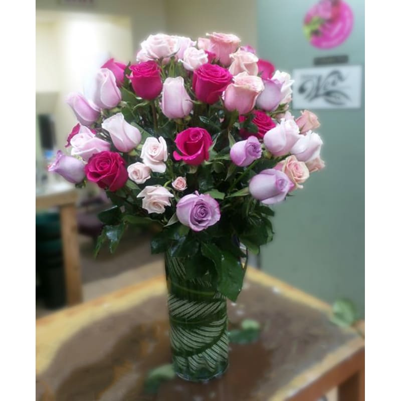 Romancing You - Premium - Pink color for any occasion. A delicate arrangement of premium long-stem roses and spray roses in various tones of pinks. Leaf-lined cylinder vase.  Note: Valentine's Day may impact the prices and availability of this product. 